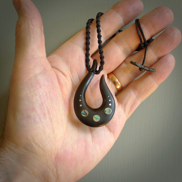 This photo shows a medium horn matau, hook pendant hand carved from horn with premium nz paua shell, Australian Golden and Tahitian Black Mother of Pearl alongside; brass, copper and silver. This is a stand out one off necklace for those who appreciate art to wear. It is provided with a cord in black that is a fixed length with Paua Shell Toggle. We ship this piece worldwide and shipping is included in the price.