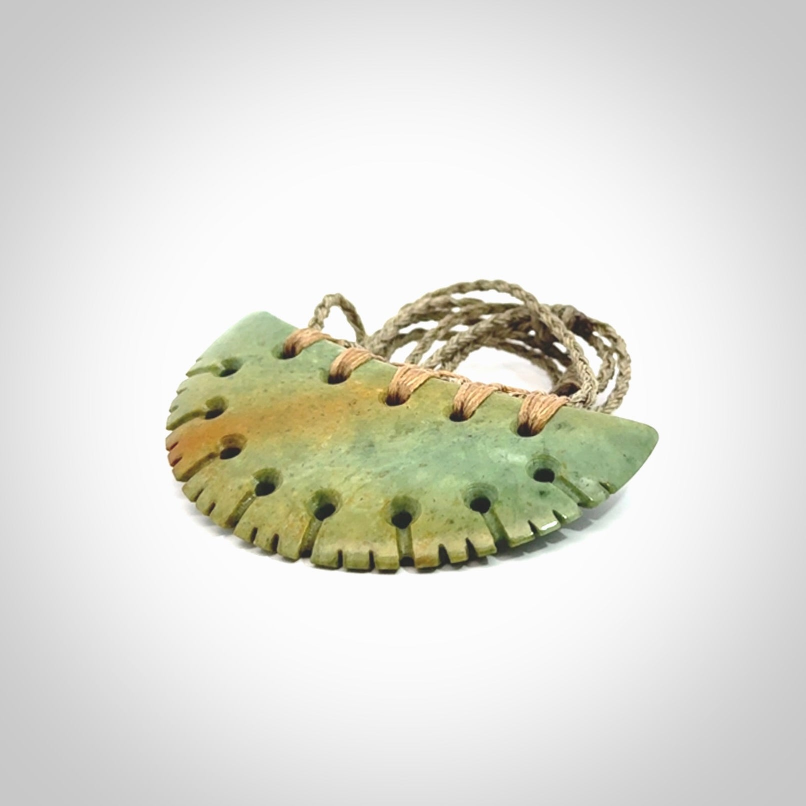 Hand carved New Zealand Flower Jade half-shield pendant.