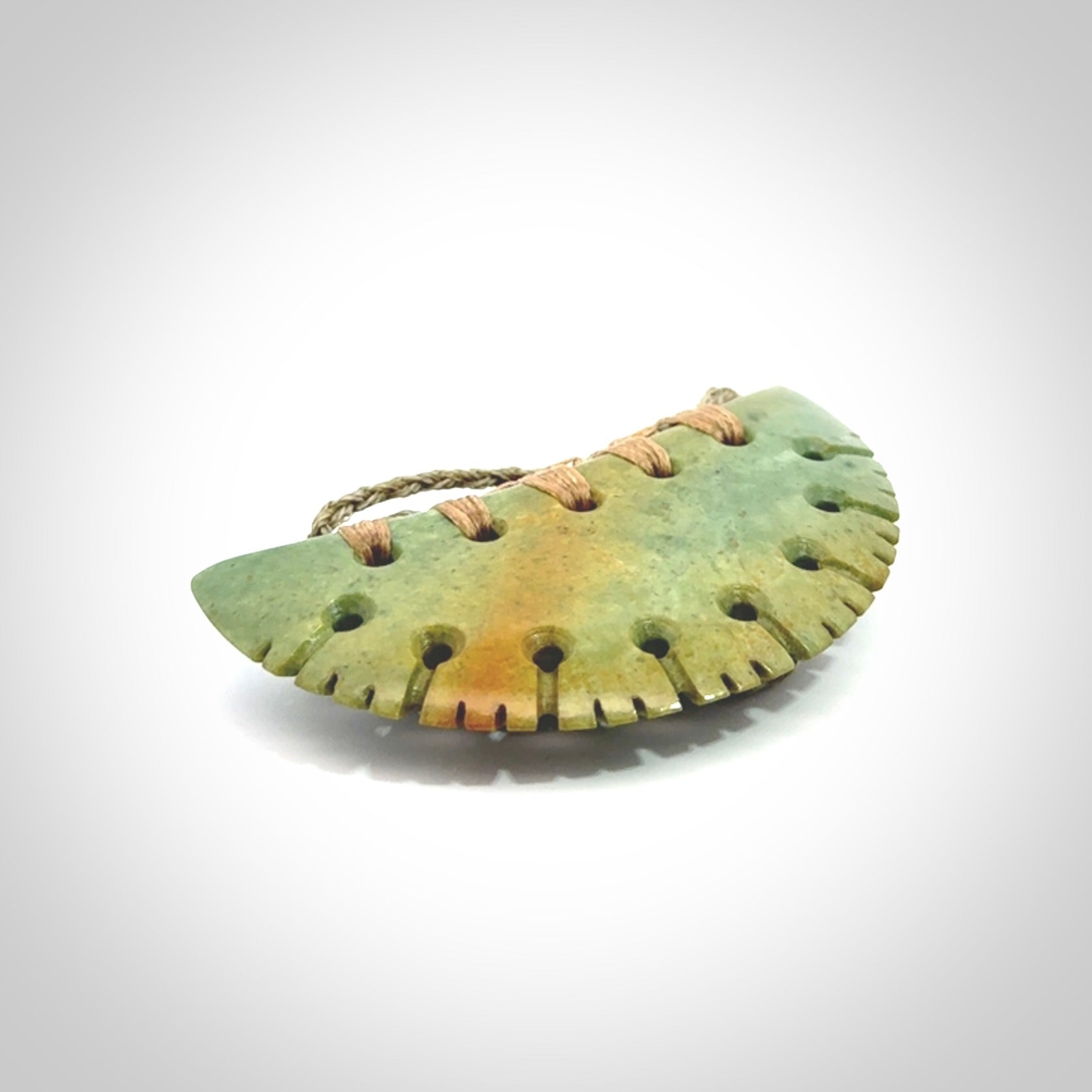 Hand carved New Zealand Flower Jade half-shield pendant.