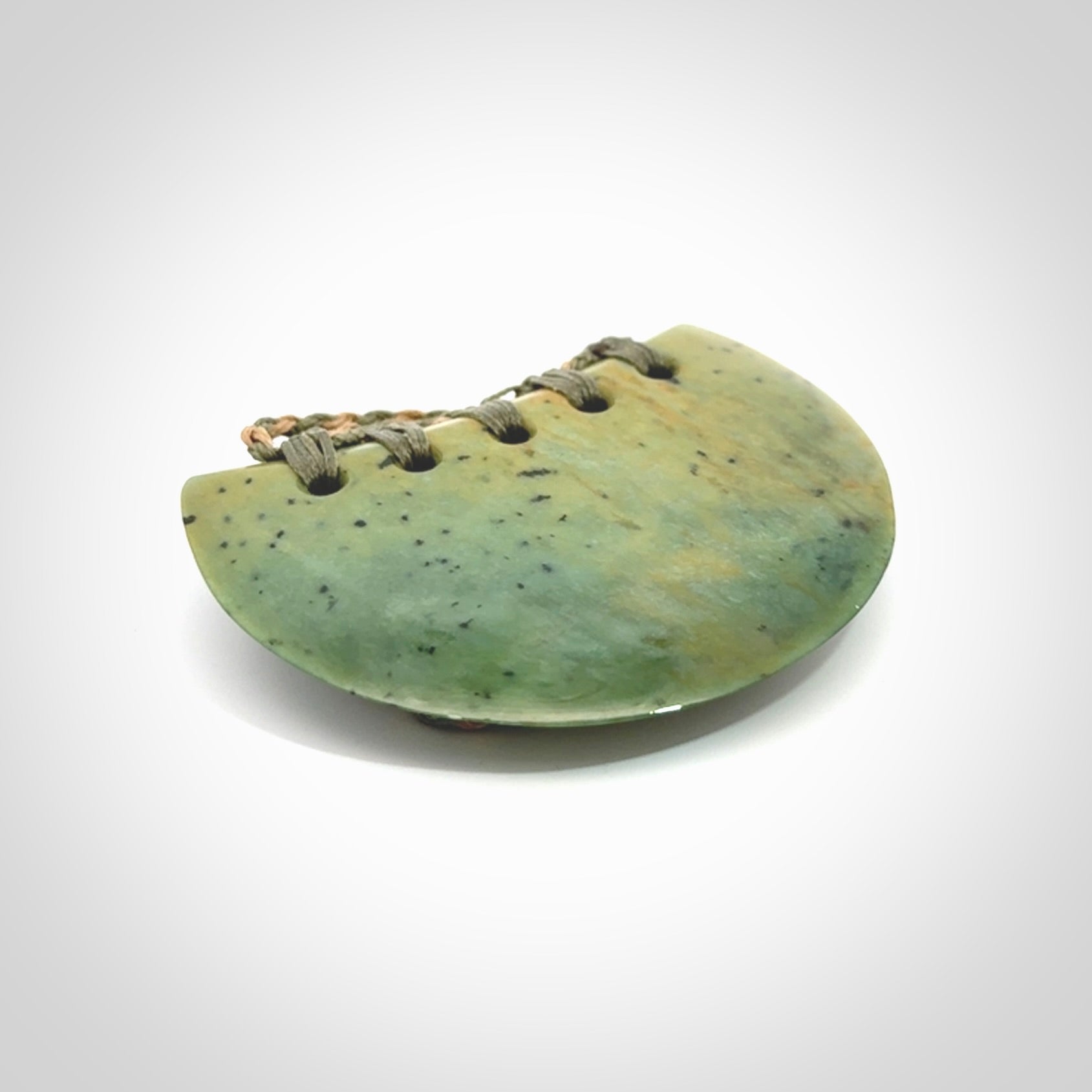 Hand carved New Zealand Flower Jade half-shield pendant.