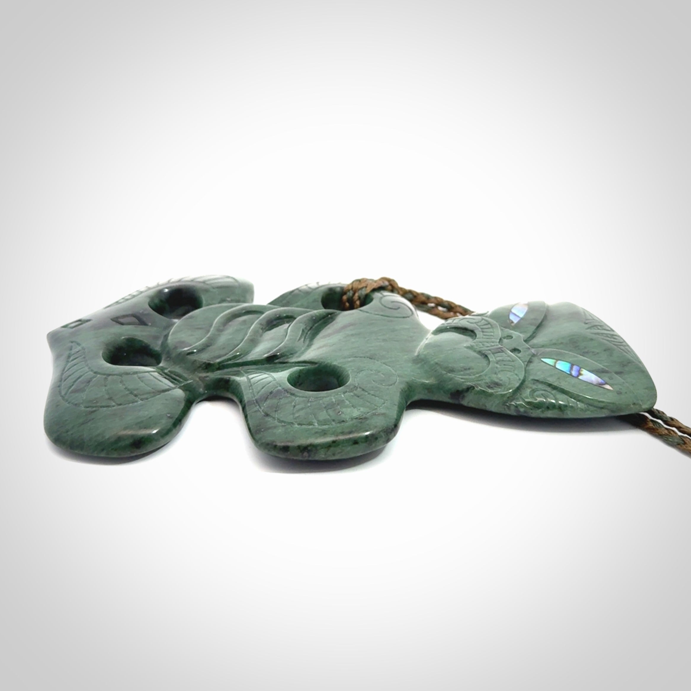This is a large hand carved New Zealand Jade tiki pendant. It is made from New Zealand Jade and Paua shell.