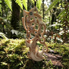 Hand carved bone manaia pendant in a forest setting