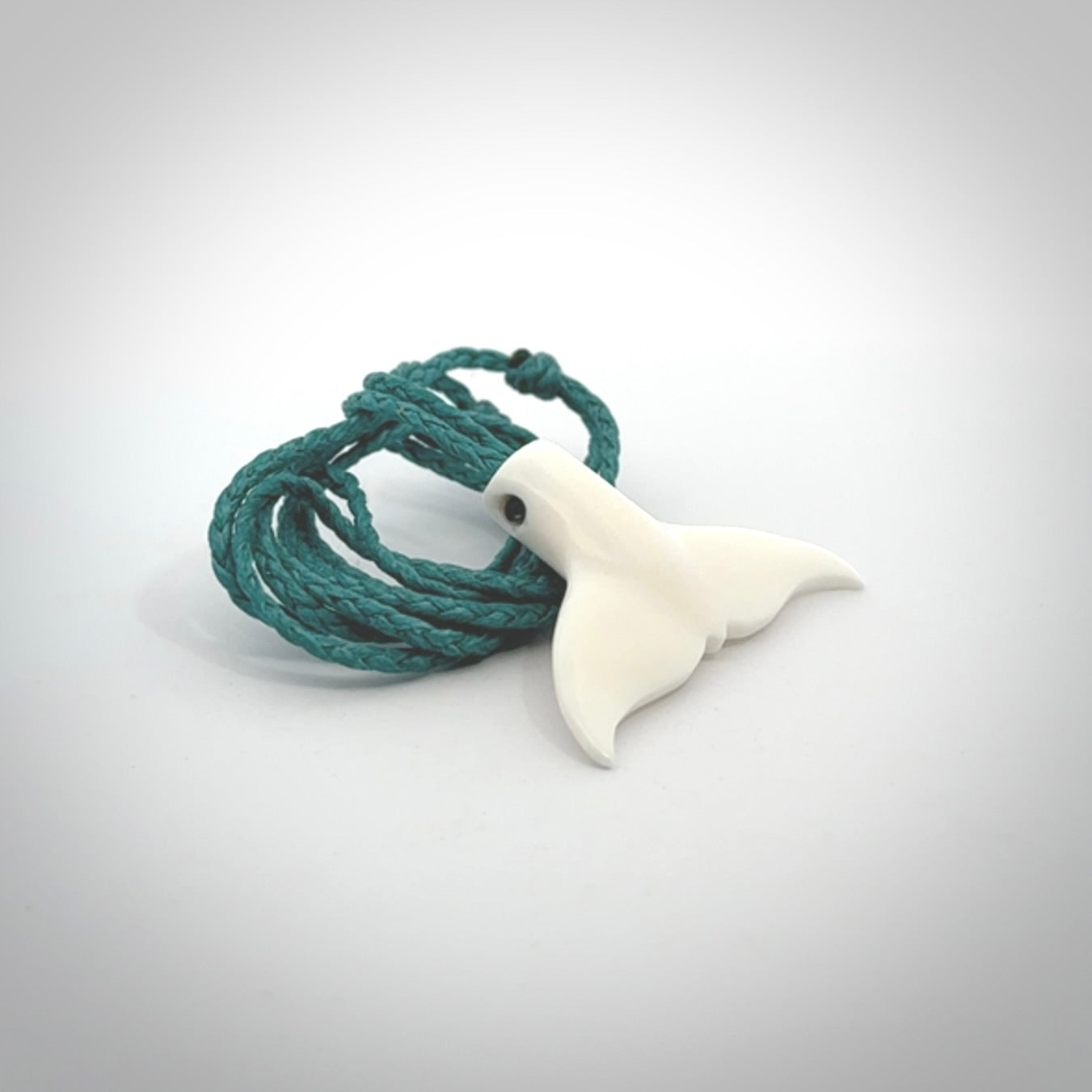 This is a lovely little Dolphin tail pendant. We have hand carved this in a bright, white bone and we make the necklace from a hand-plaited waxed cord. These are original NZ Pacific pendants, handmade from natural materials.