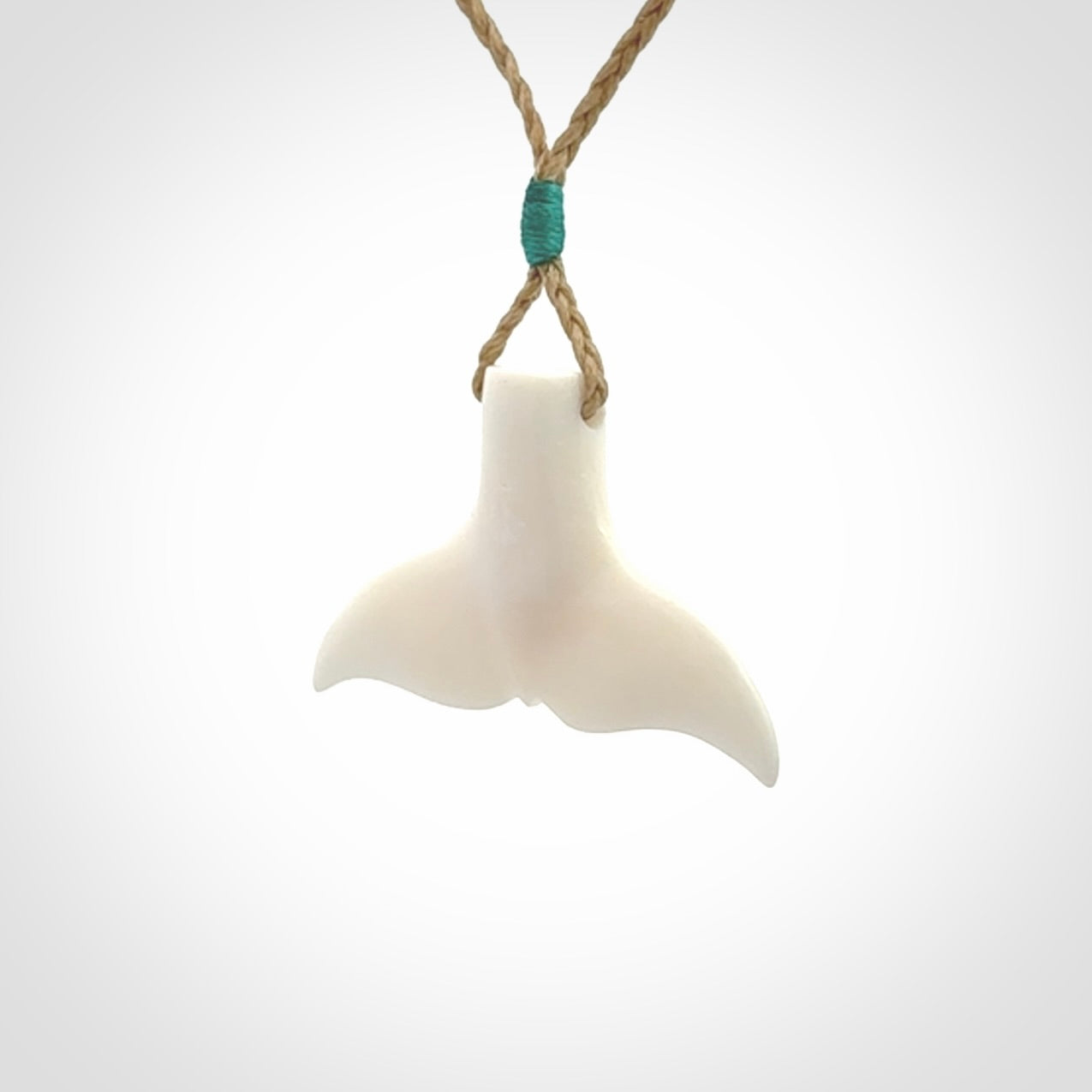 This is a lovely little Dolphin tail pendant. We have hand carved this in a bright, white bone and we make the necklace from a hand-plaited waxed cord. These are original NZ Pacific pendants, handmade from natural materials.
