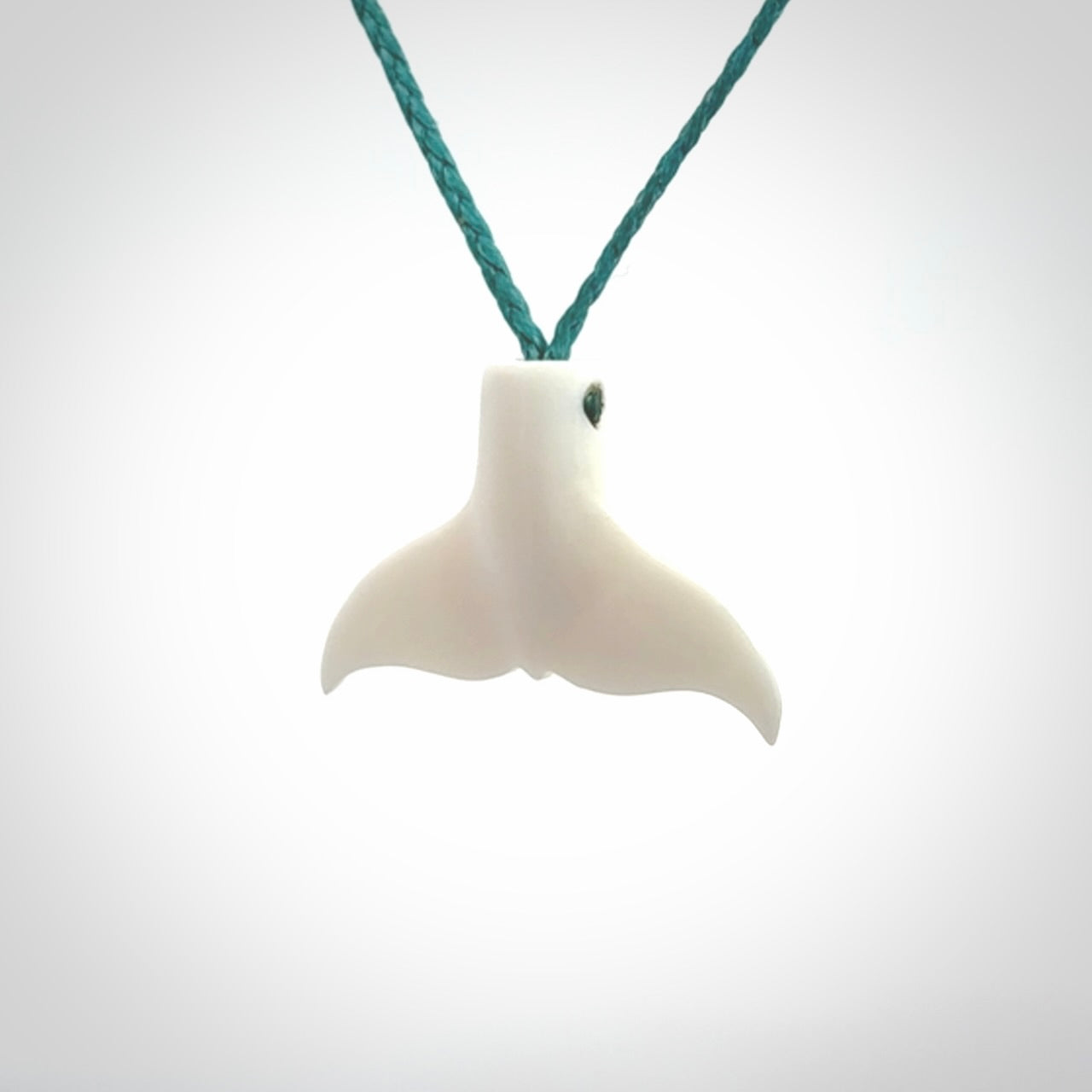 This is a lovely little Dolphin tail pendant. We have hand carved this in a bright, white bone and we make the necklace from a hand-plaited waxed cord. These are original NZ Pacific pendants, handmade from natural materials.