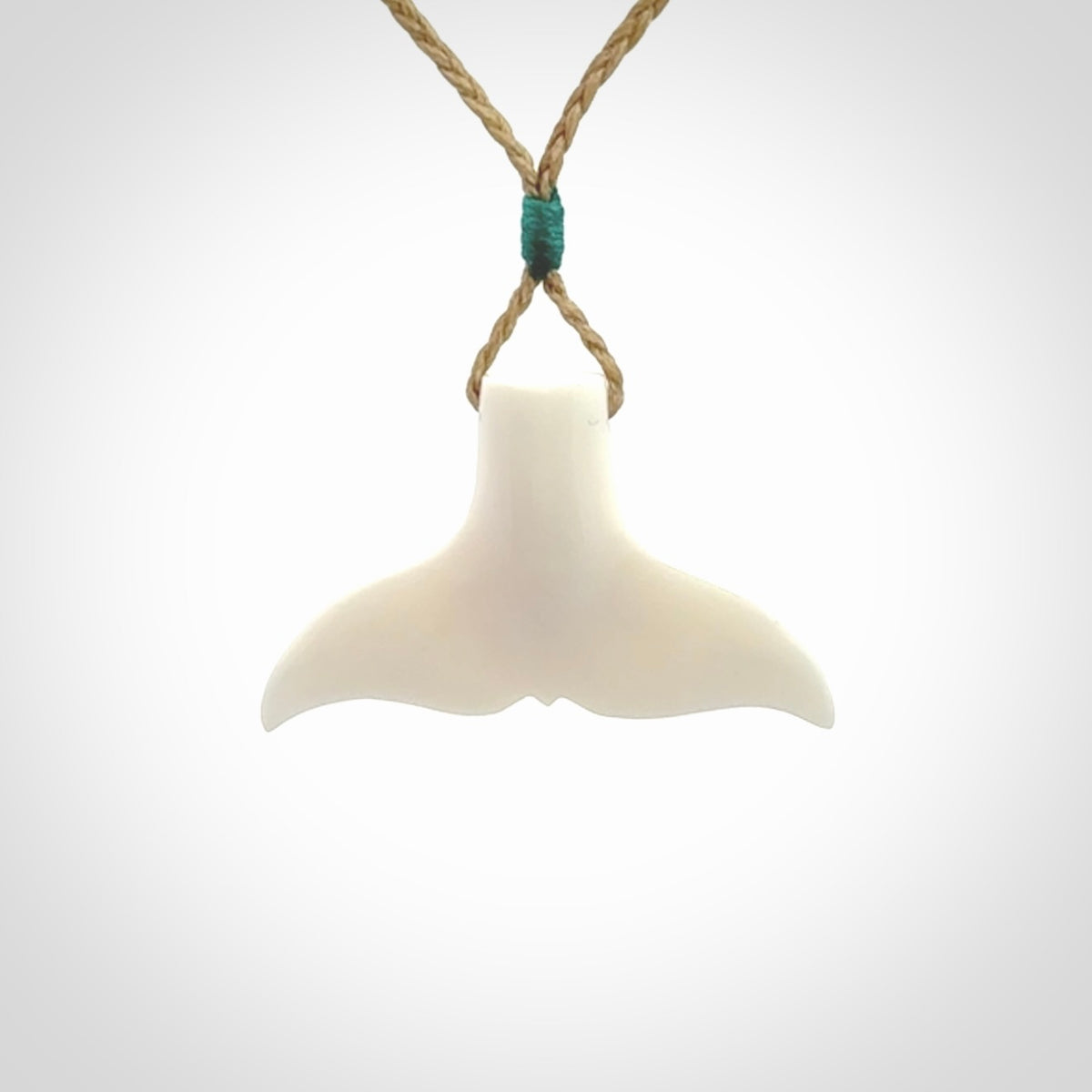 This is a lovely little Dolphin tail pendant. We have hand carved this in a bright, white bone and we make the necklace from a hand-plaited waxed cord. These are original NZ Pacific pendants, handmade from natural materials.