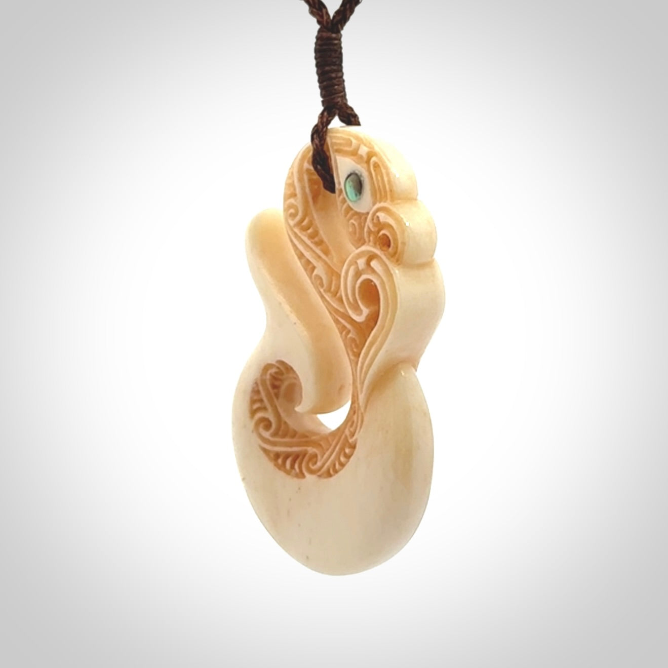 This picture shows a carved manaia in bone. It is provided with a hand-plaited brown cord that is length adjustable.