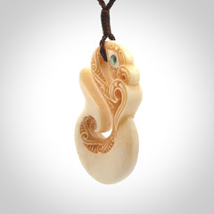 This picture shows a carved manaia in bone. It is provided with a hand-plaited brown cord that is length adjustable.
