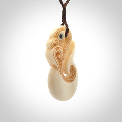 This picture shows a carved manaia in bone. It is provided with a hand-plaited brown cord that is length adjustable.