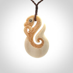 This picture shows a carved manaia in bone. It is provided with a hand-plaited brown cord that is length adjustable.