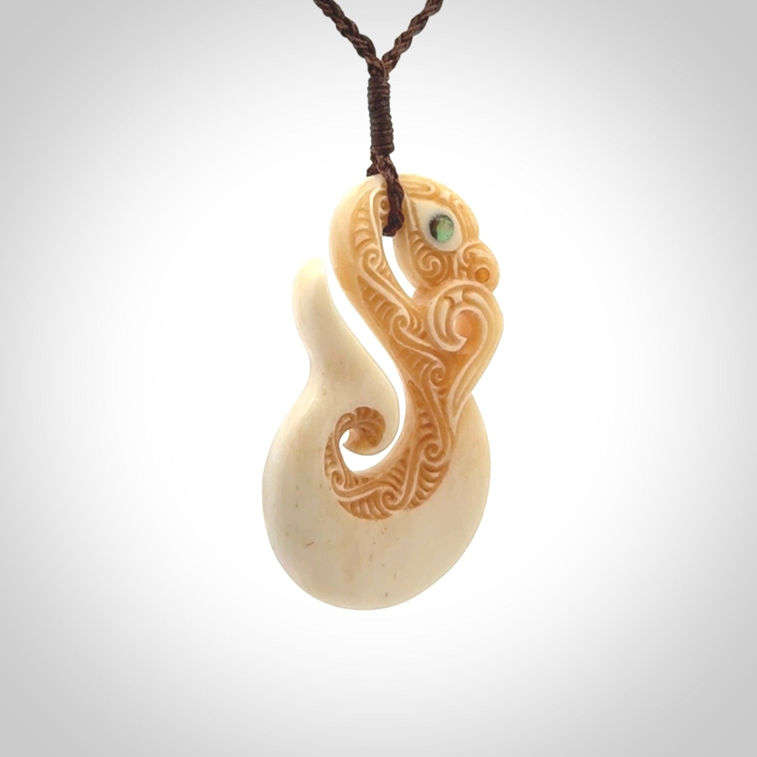 This picture shows a carved manaia in bone. It is provided with a hand-plaited brown cord that is length adjustable.