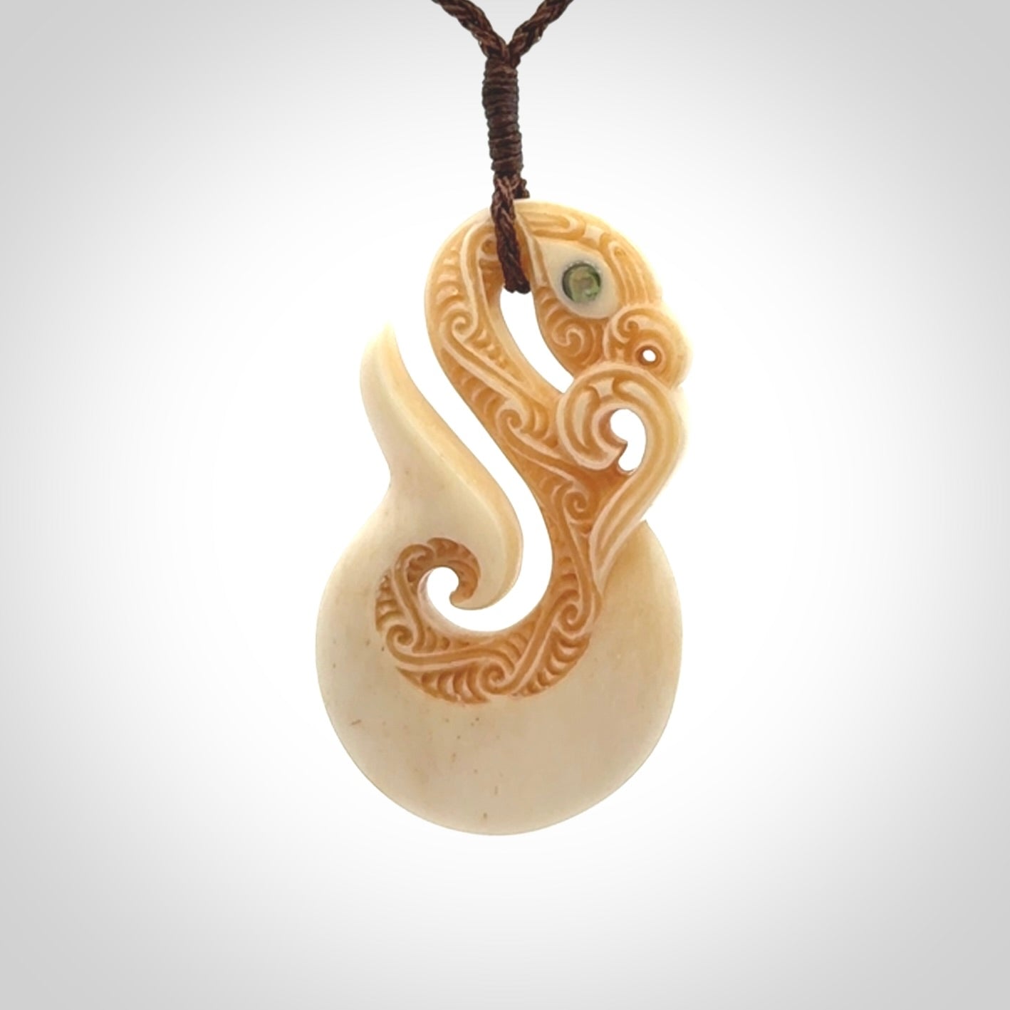 This picture shows a carved manaia in bone. It is provided with a hand-plaited brown cord that is length adjustable.