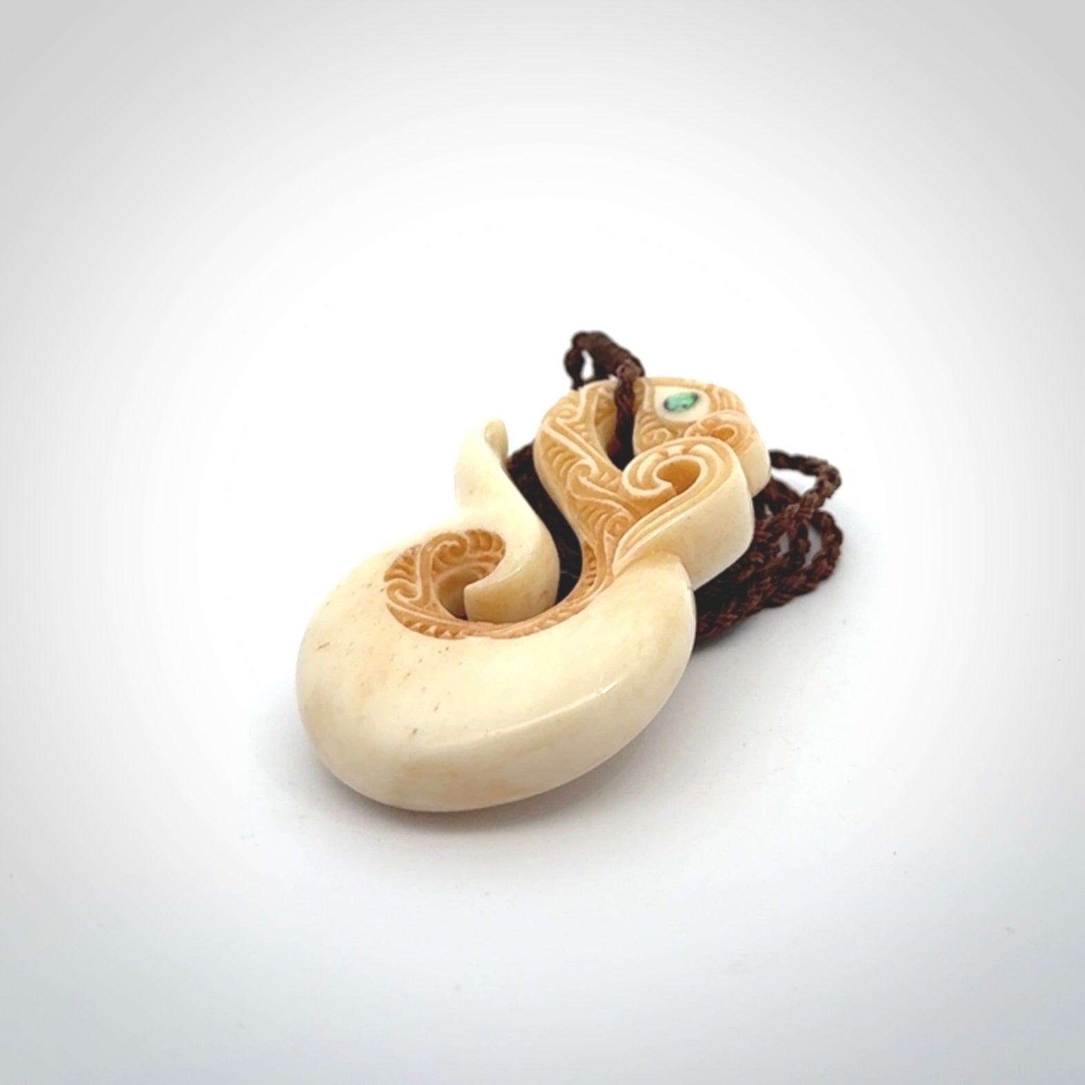 This picture shows a carved manaia in bone. It is provided with a hand-plaited brown cord that is length adjustable.