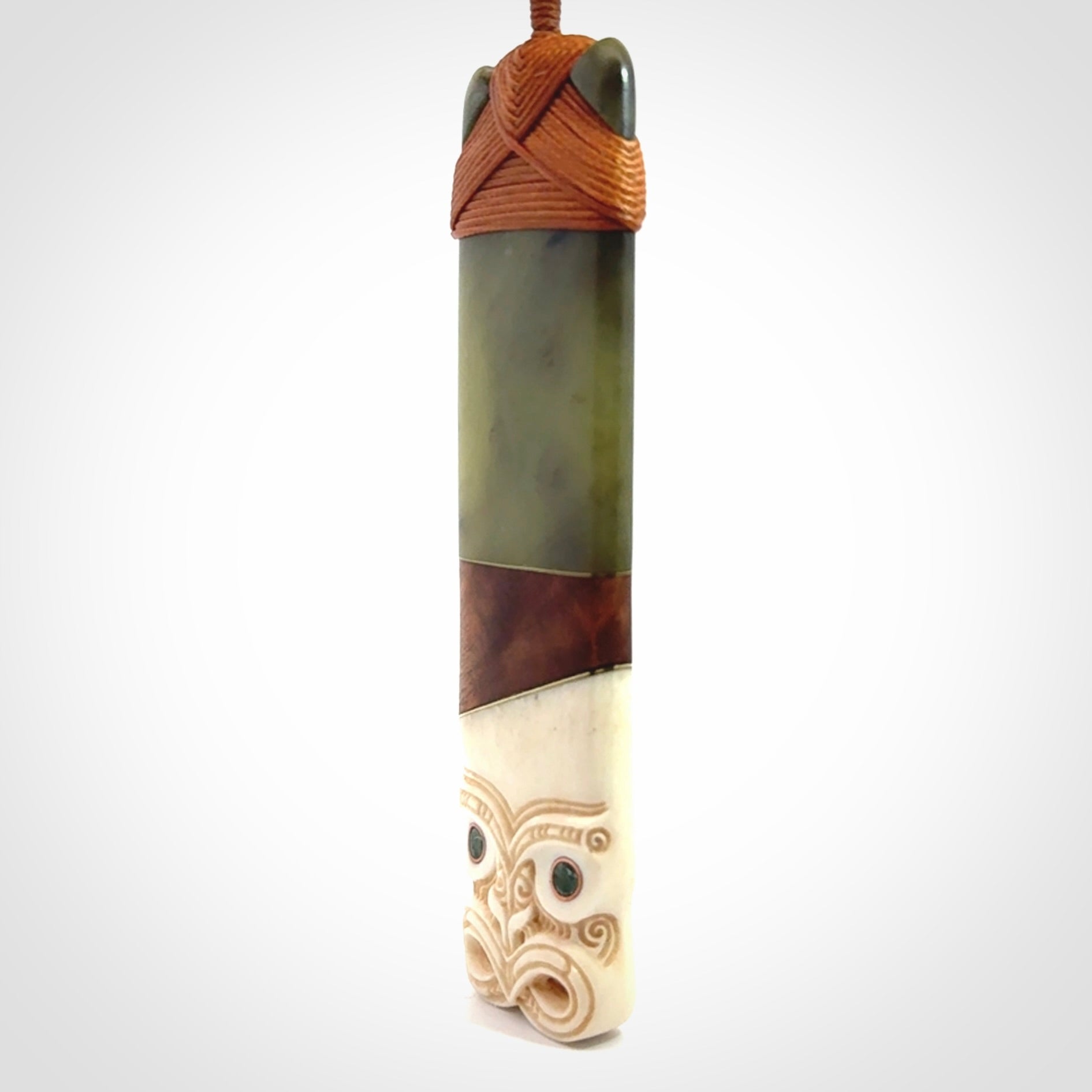 This is a large carved Koruru pendant. It is made from New Zealand Jade, Bone, Kauri wood and Brass. The face of the Koruru is carved with a traditional design in the front. It has a protruding tongue which is also carved and the back face has traditional carved designs. This is a large and very traditional pendant that is a collectors piece.