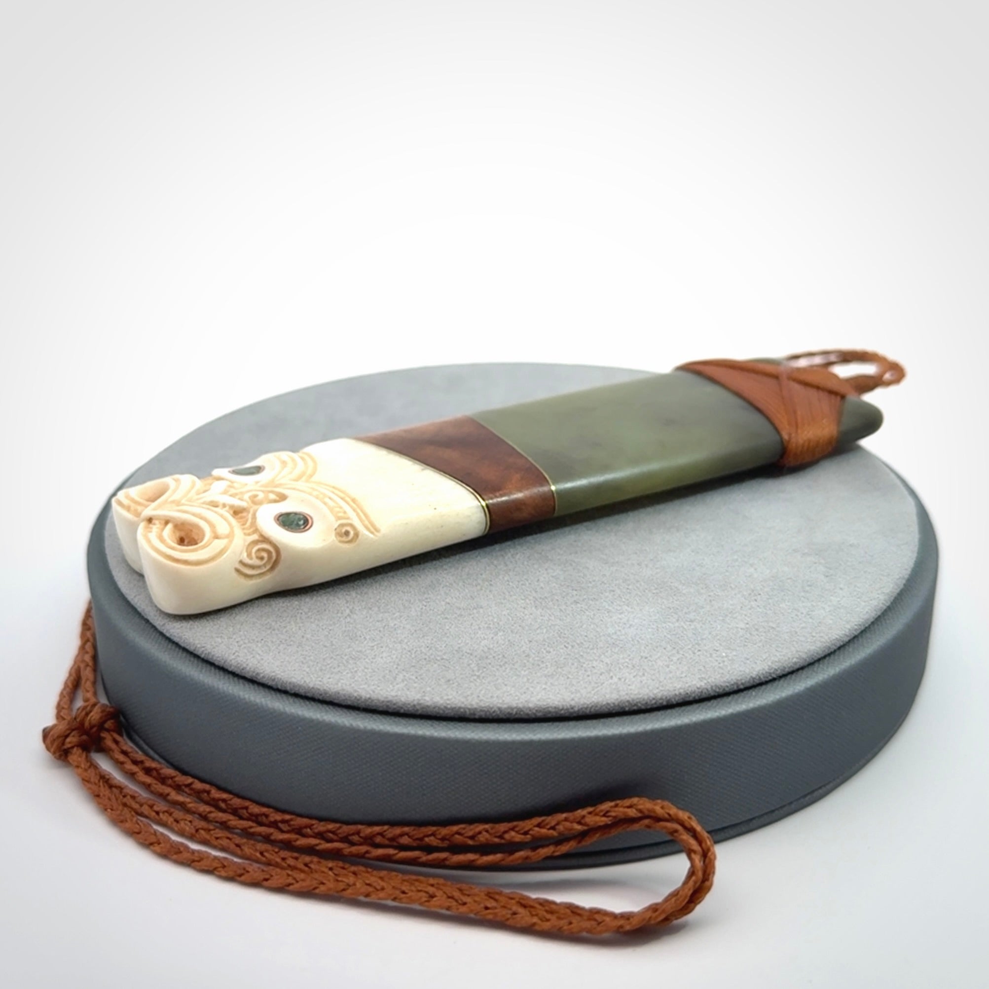 This is a large carved Koruru pendant. It is made from New Zealand Jade, Bone, Kauri wood and Brass. The face of the Koruru is carved with a traditional design in the front. It has a protruding tongue which is also carved and the back face has traditional carved designs. This is a large and very traditional pendant that is a collectors piece.