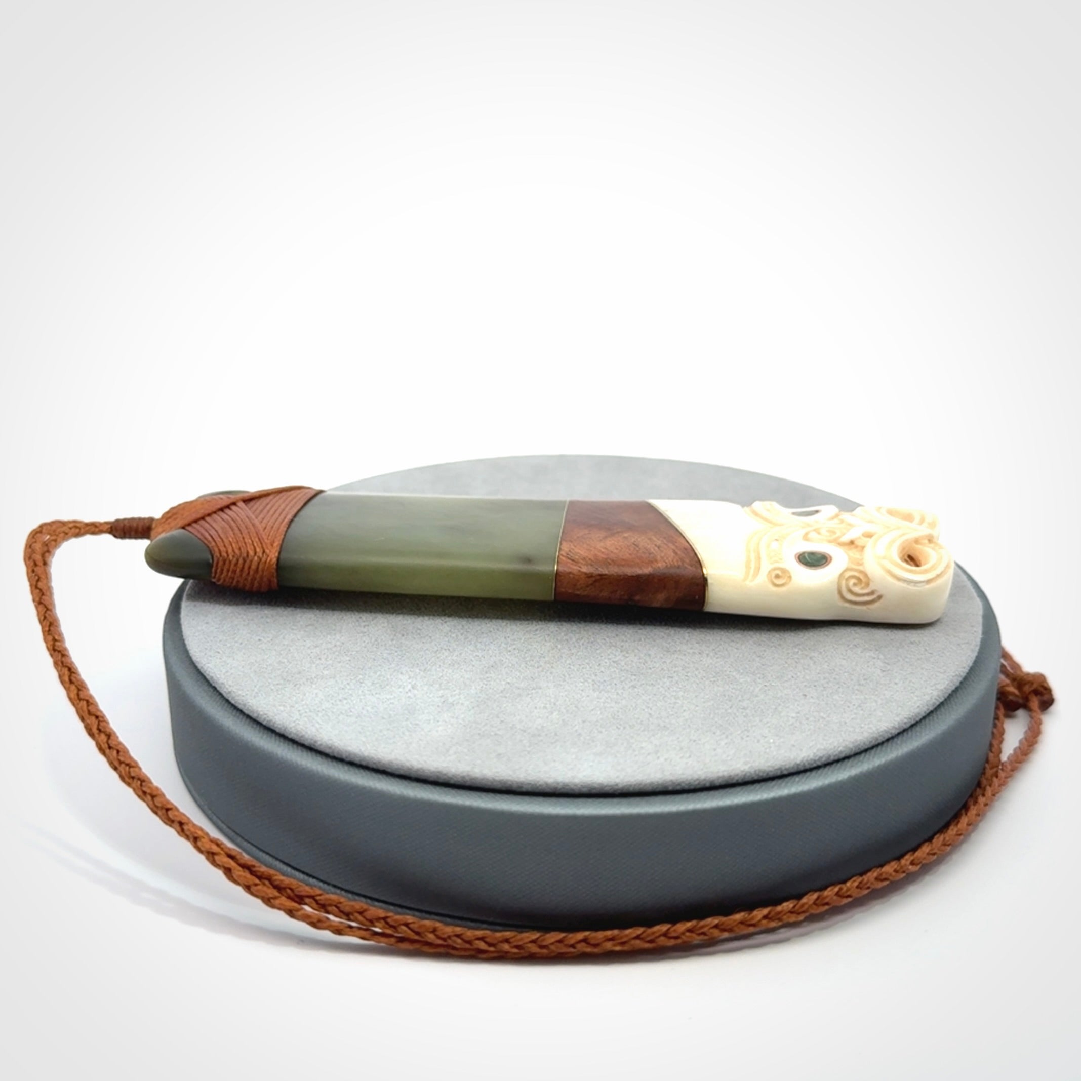 This is a large carved Koruru pendant. It is made from New Zealand Jade, Bone, Kauri wood and Brass. The face of the Koruru is carved with a traditional design in the front. It has a protruding tongue which is also carved and the back face has traditional carved designs. This is a large and very traditional pendant that is a collectors piece.
