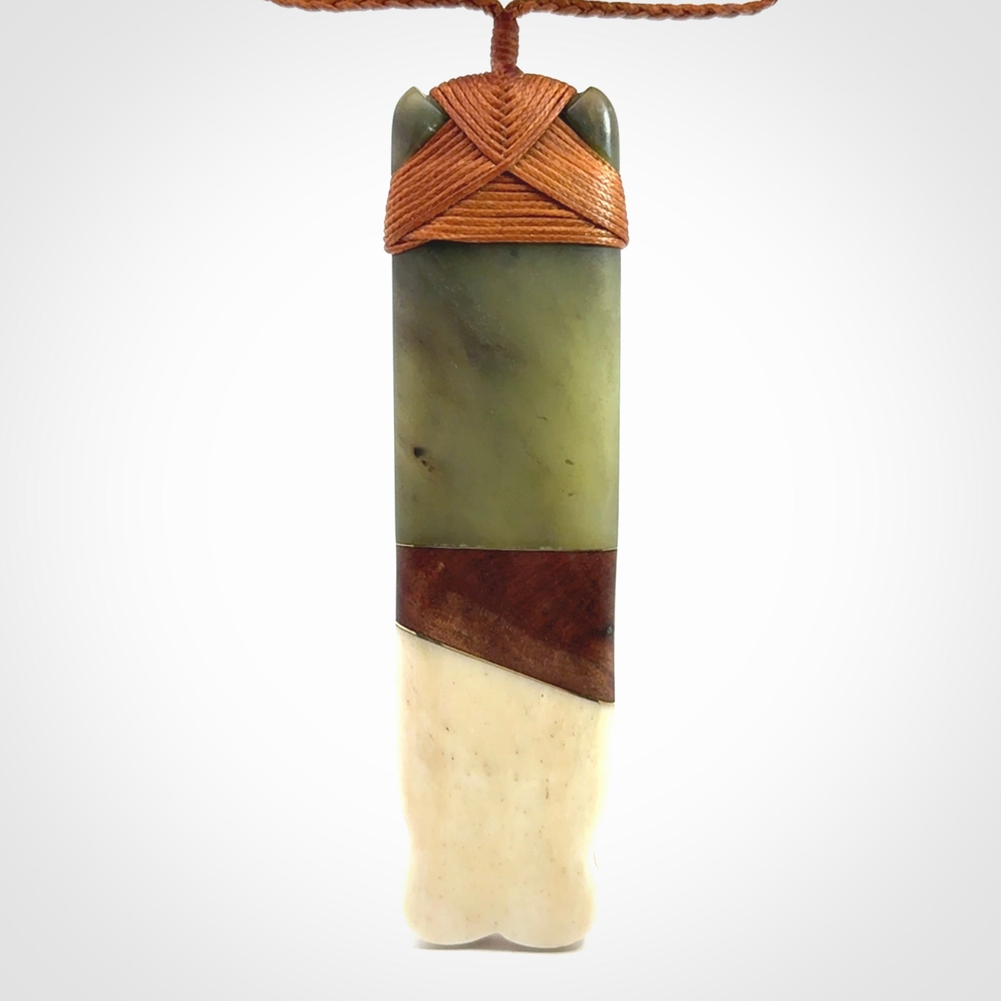 This is a large carved Koruru pendant. It is made from New Zealand Jade, Bone, Kauri wood and Brass. The face of the Koruru is carved with a traditional design in the front. It has a protruding tongue which is also carved and the back face has traditional carved designs. This is a large and very traditional pendant that is a collectors piece.