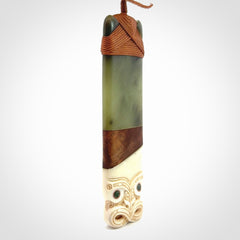 This is a large carved Koruru pendant. It is made from New Zealand Jade, Bone, Kauri wood and Brass. The face of the Koruru is carved with a traditional design in the front. It has a protruding tongue which is also carved and the back face has traditional carved designs. This is a large and very traditional pendant that is a collectors piece.