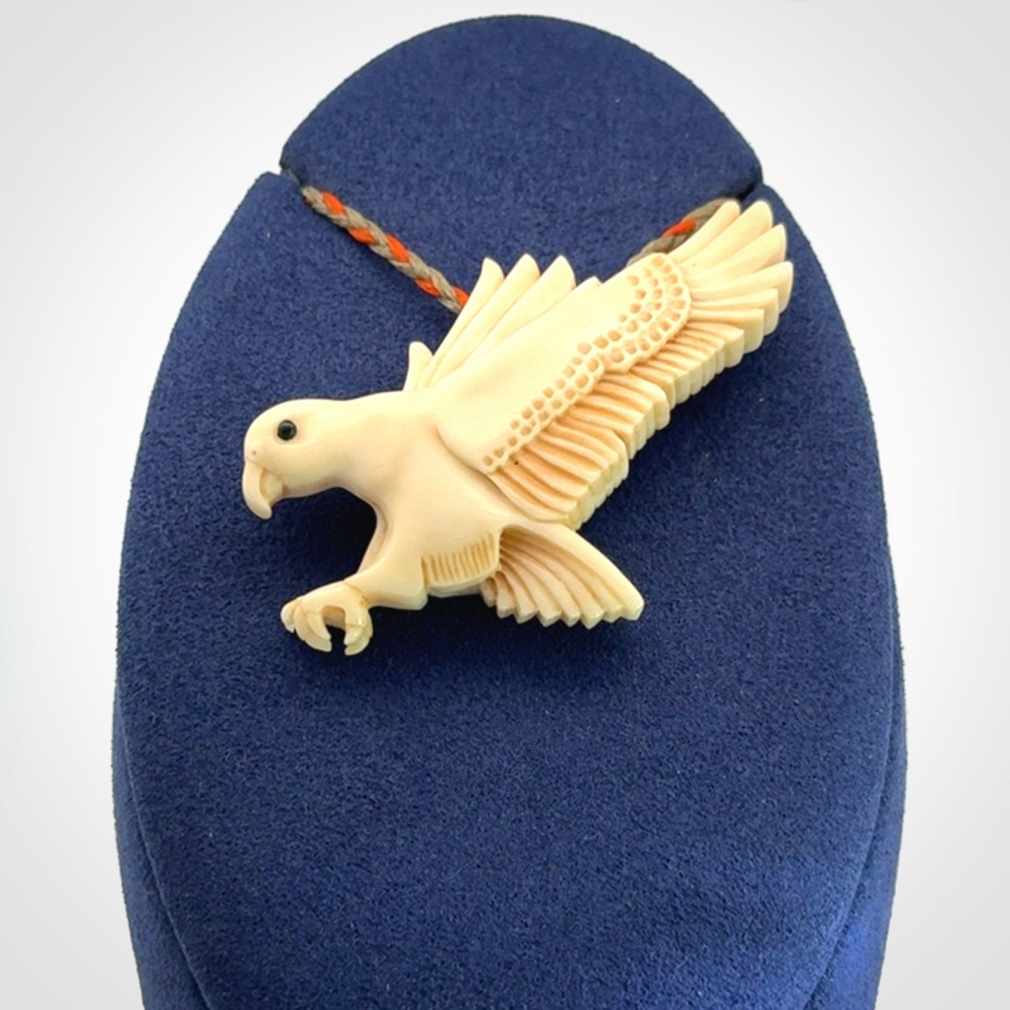 This picture shows a carved kea pendant in bone. It is provided with a hand-plaited orange and olive cord that is length adjustable. Shipping is included and we ship worldwide.