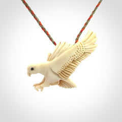 This picture shows a carved kea pendant in bone. It is provided with a hand-plaited orange and olive cord that is length adjustable. Shipping is included and we ship worldwide.