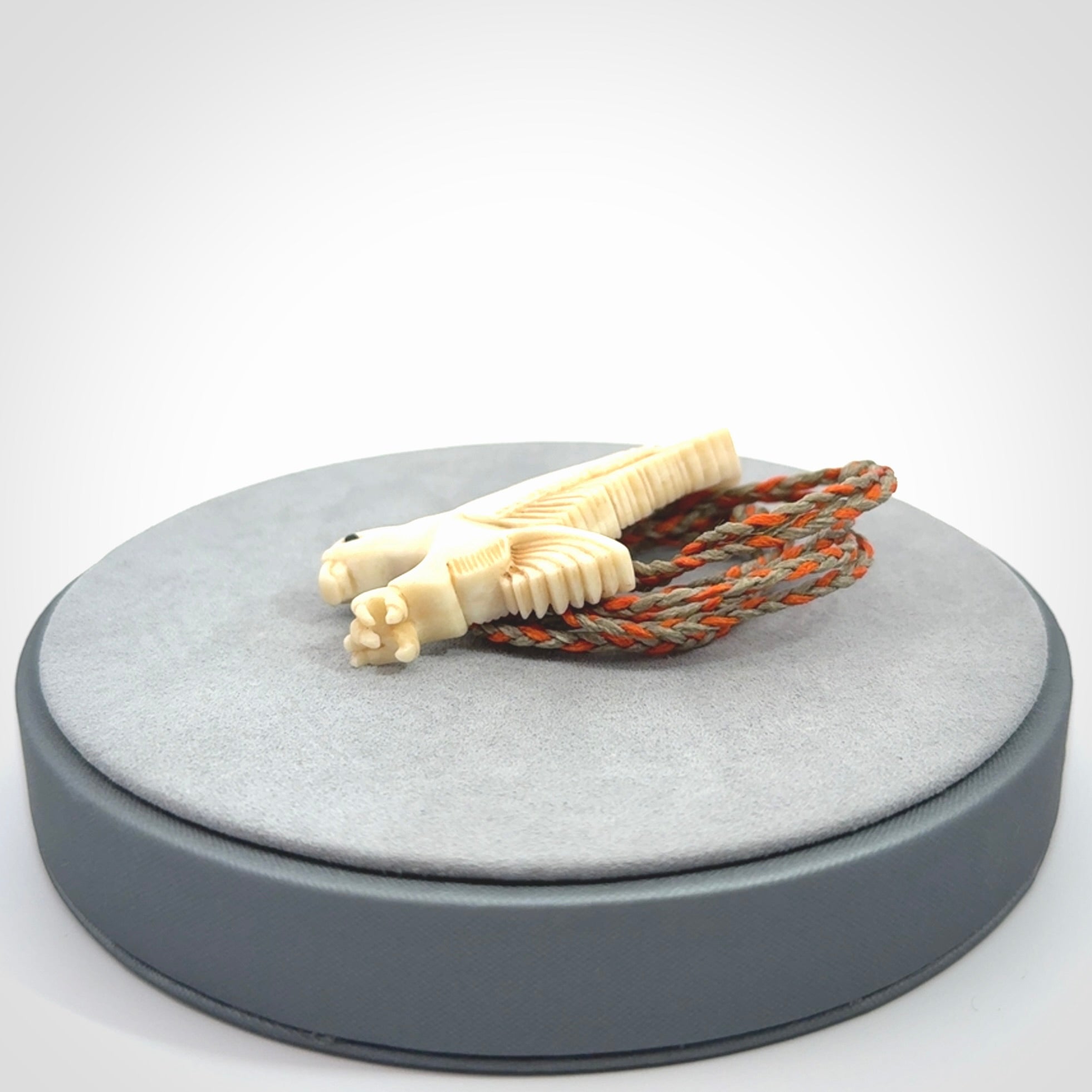 This picture shows a carved kea pendant in bone. It is provided with a hand-plaited orange and olive cord that is length adjustable. Shipping is included and we ship worldwide.