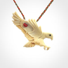 This picture shows a carved kea pendant in bone. It is provided with a hand-plaited orange and olive cord that is length adjustable. Shipping is included and we ship worldwide.