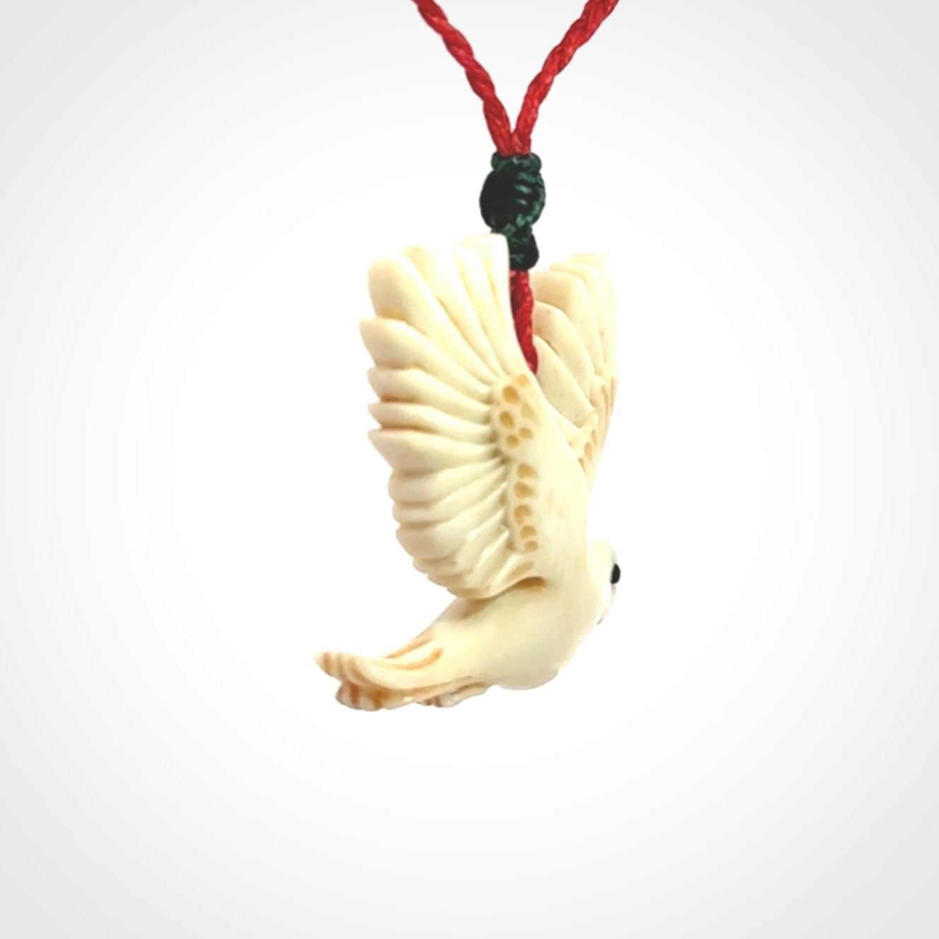 This picture shows a carved kea pendant in bone. It is provided with a hand-plaited red cord that is length adjustable. Shipping is included and we ship worldwide.