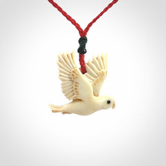 This picture shows a carved kea pendant in bone. It is provided with a hand-plaited red cord that is length adjustable. Shipping is included and we ship worldwide.