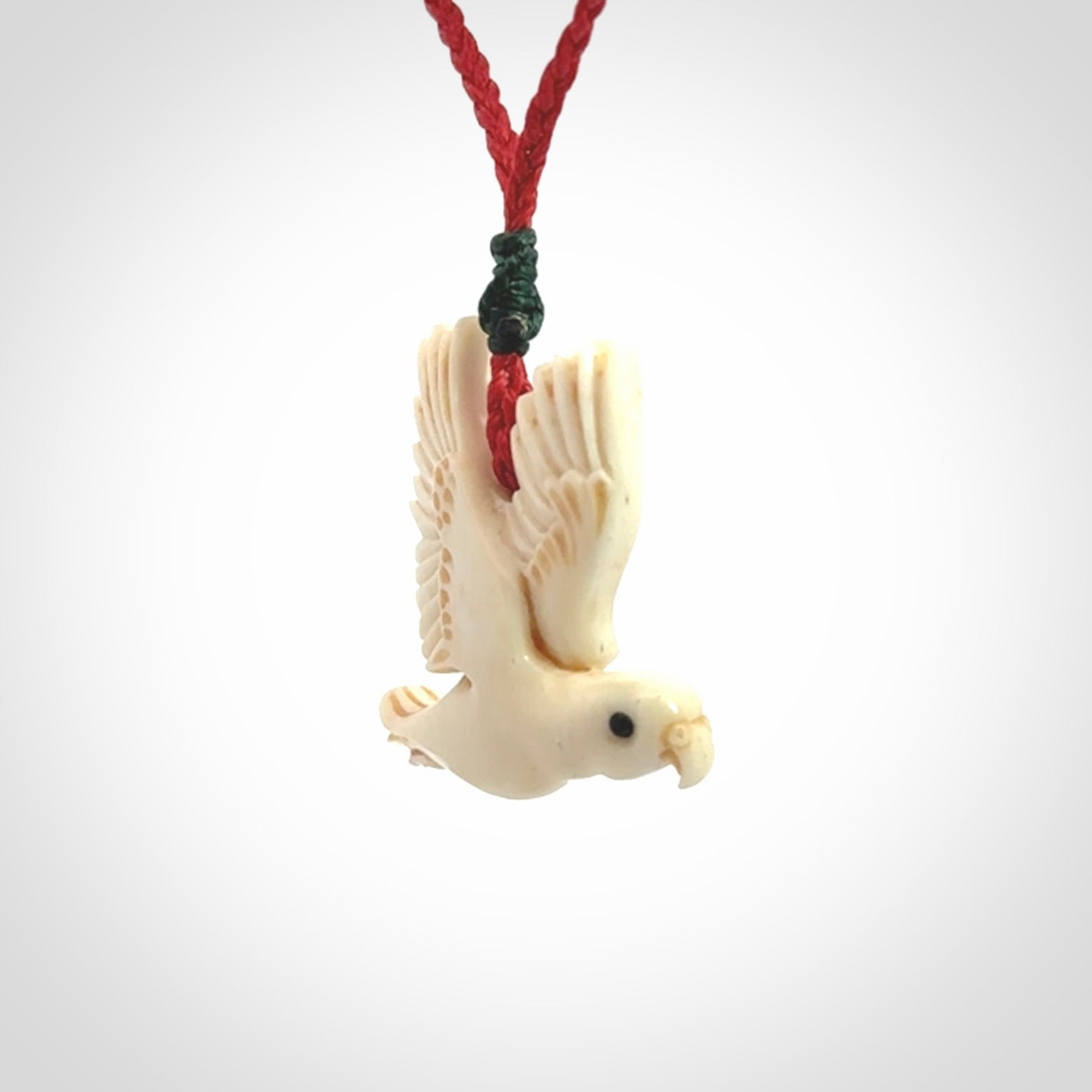 This picture shows a carved kea pendant in bone. It is provided with a hand-plaited red cord that is length adjustable. Shipping is included and we ship worldwide.