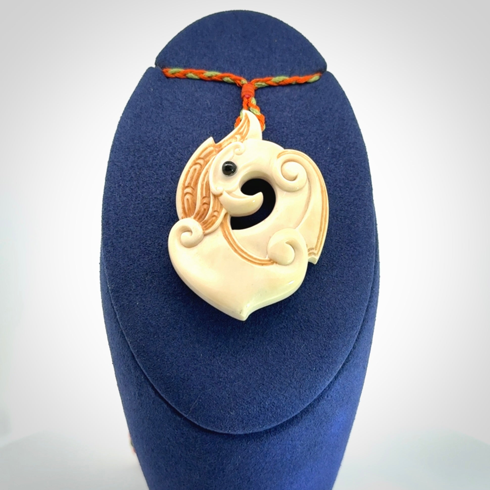 This picture shows a carved kea pendant in bone. It is provided with a hand-plaited orange and green cord that is length adjustable. Shipping is included and we ship worldwide.