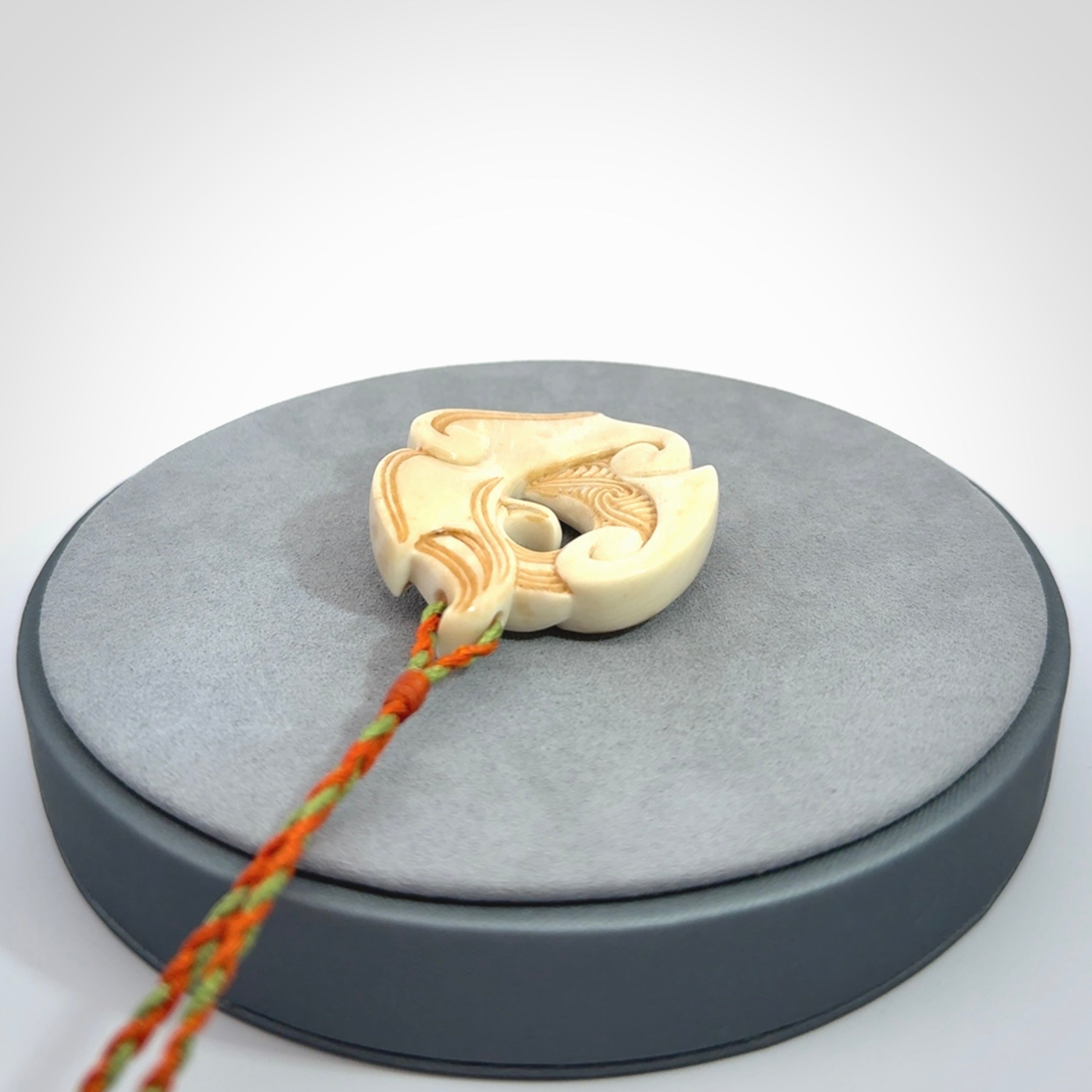 This picture shows a carved kea pendant in bone. It is provided with a hand-plaited orange and green cord that is length adjustable. Shipping is included and we ship worldwide.