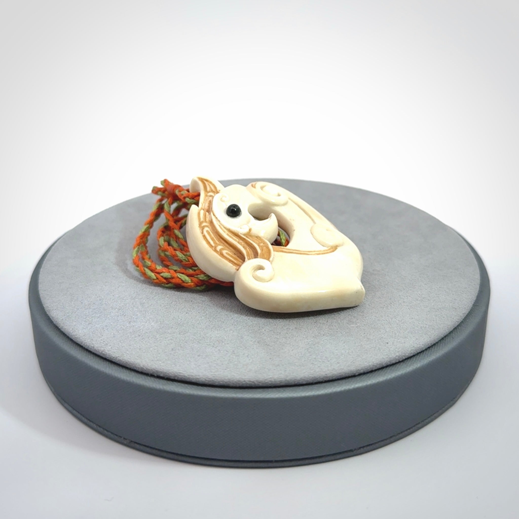 This picture shows a carved kea pendant in bone. It is provided with a hand-plaited orange and green cord that is length adjustable. Shipping is included and we ship worldwide.