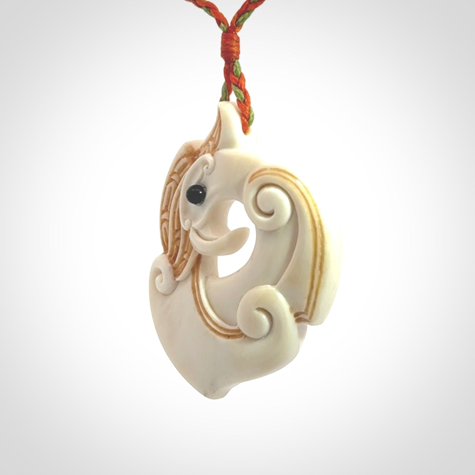 This picture shows a carved kea pendant in bone. It is provided with a hand-plaited orange and green cord that is length adjustable. Shipping is included and we ship worldwide.