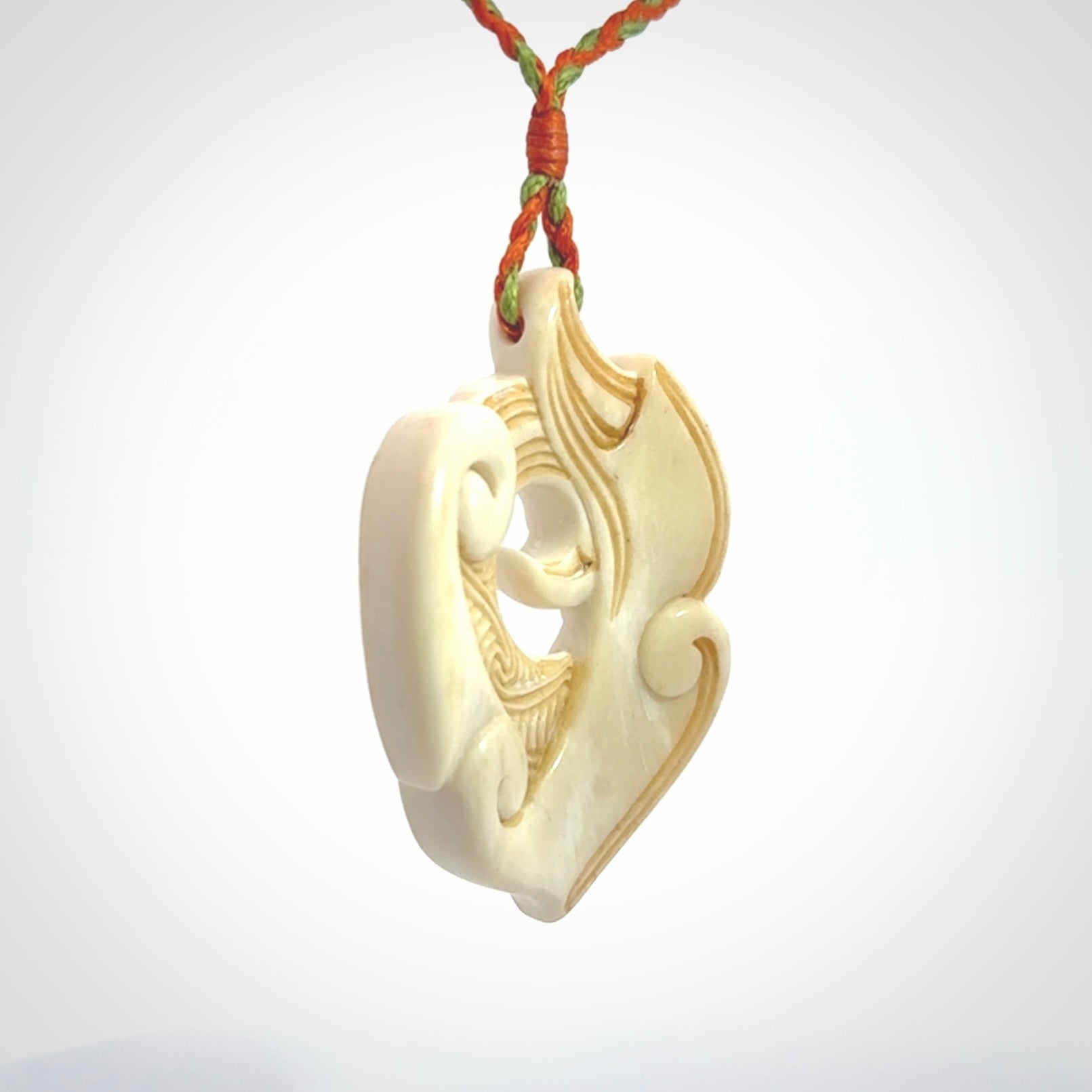 This picture shows a carved kea pendant in bone. It is provided with a hand-plaited orange and green cord that is length adjustable. Shipping is included and we ship worldwide.