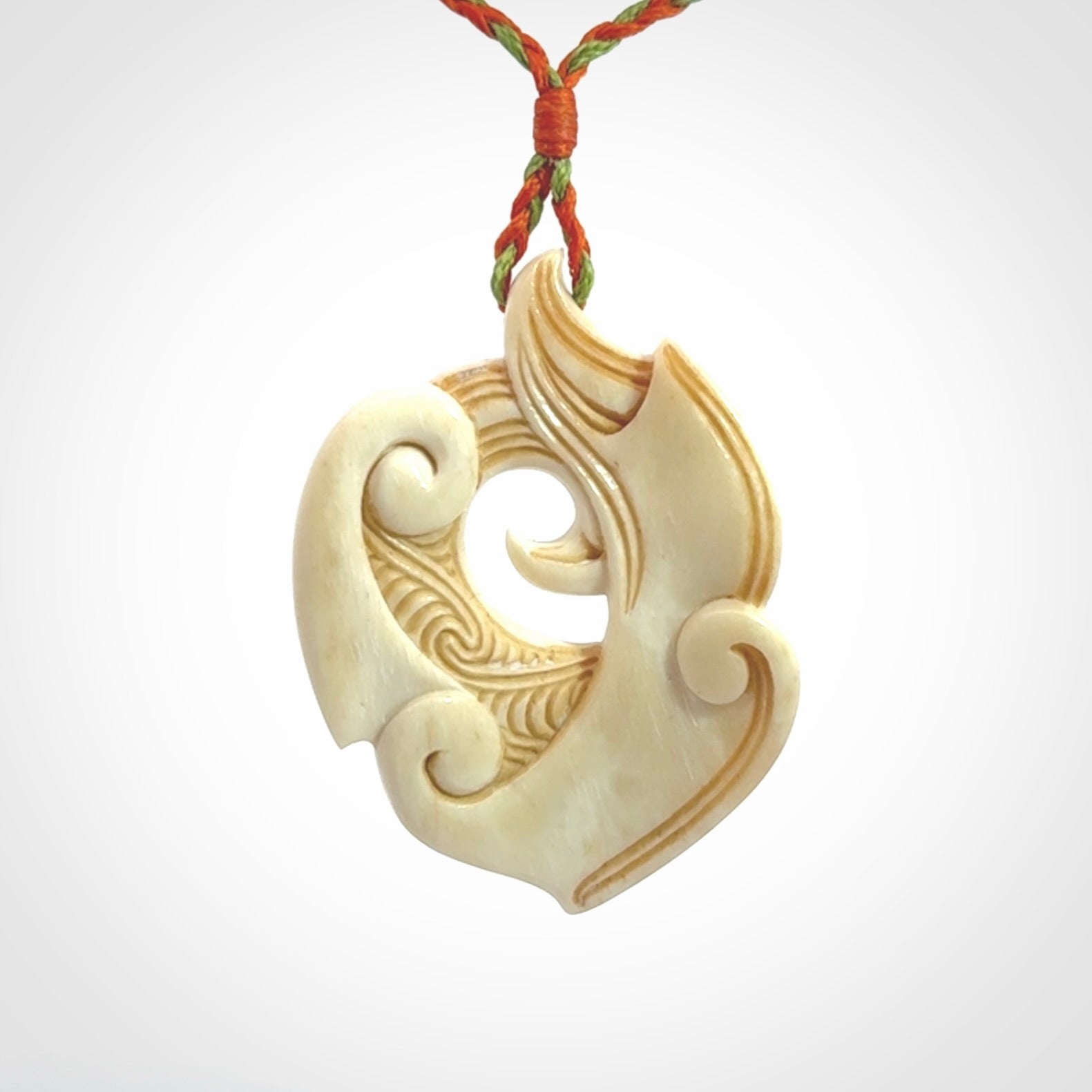 This picture shows a carved kea pendant in bone. It is provided with a hand-plaited orange and green cord that is length adjustable. Shipping is included and we ship worldwide.