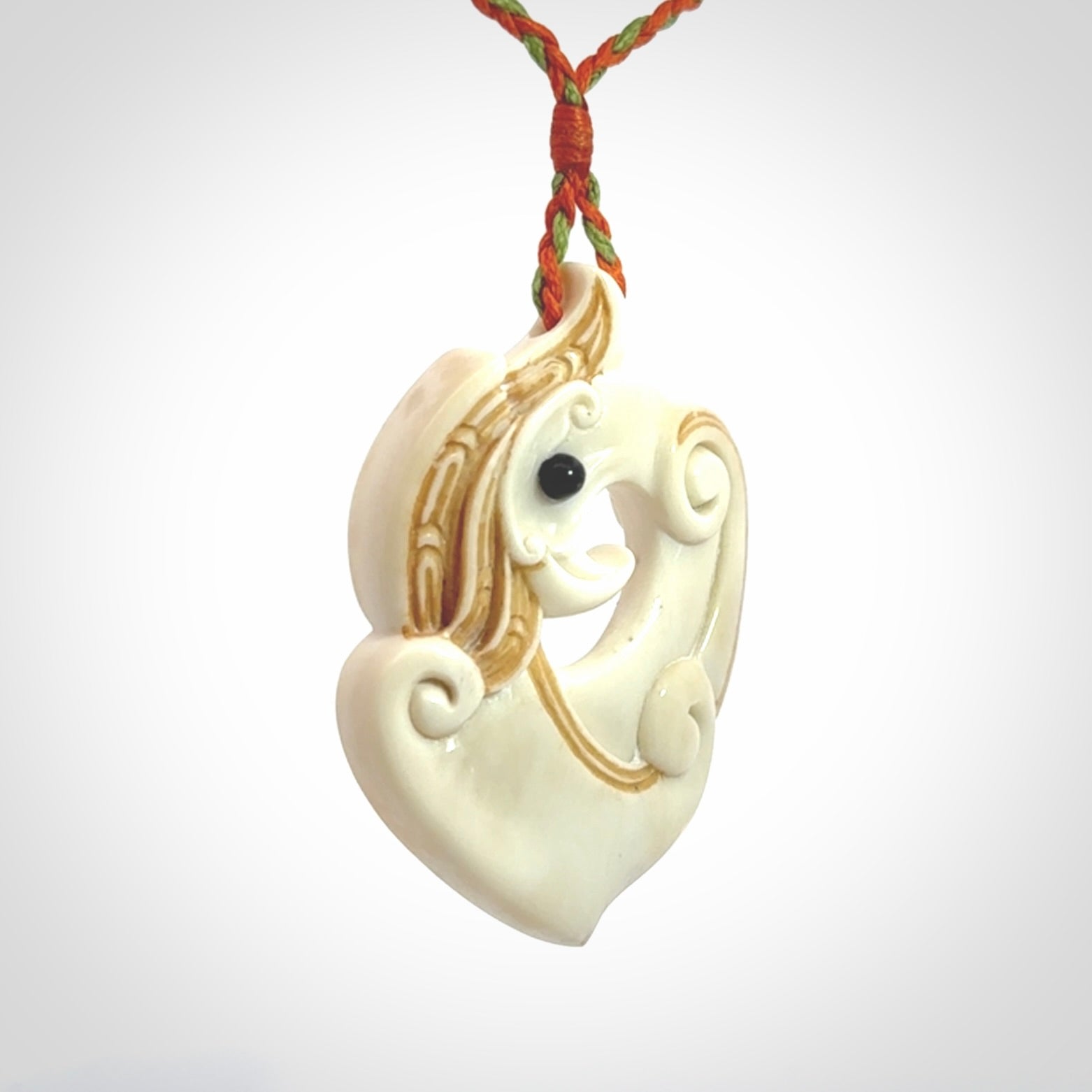 This picture shows a carved kea pendant in bone. It is provided with a hand-plaited orange and green cord that is length adjustable. Shipping is included and we ship worldwide.