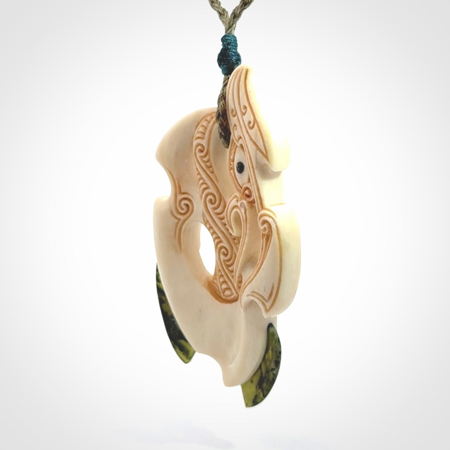 This picture shows a carved manaia in bone with Jade and Paua shell. It is provided with a hand-plaited fern green cord that is length adjustable. Free shipping worldwide.