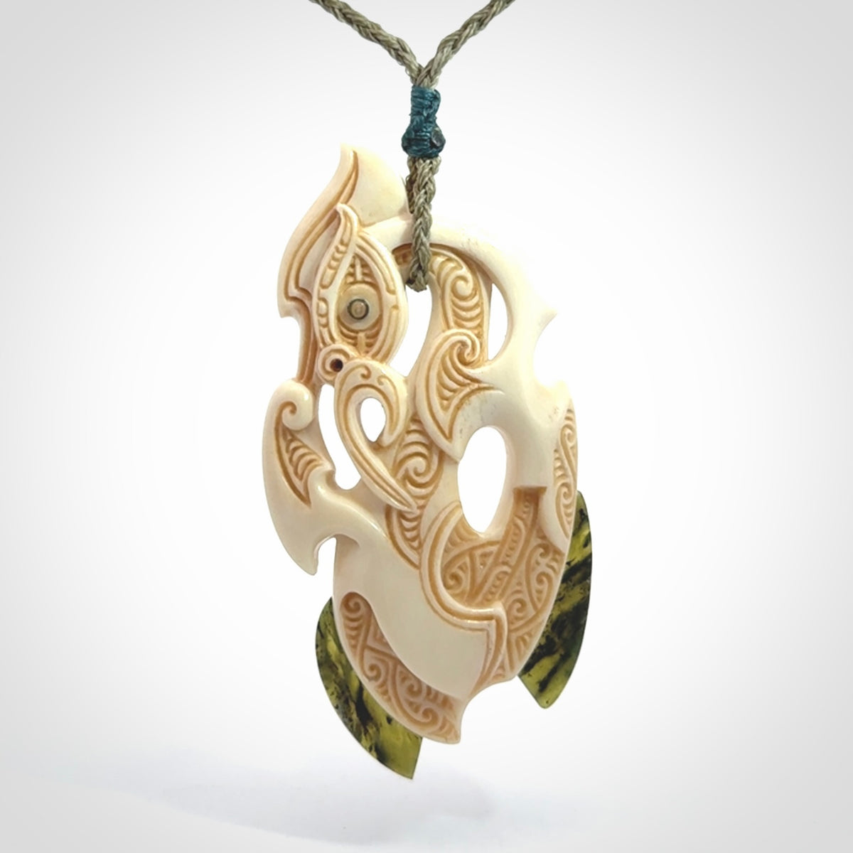 This picture shows a carved manaia in bone with Jade and Paua shell. It is provided with a hand-plaited fern green cord that is length adjustable. Free shipping worldwide.