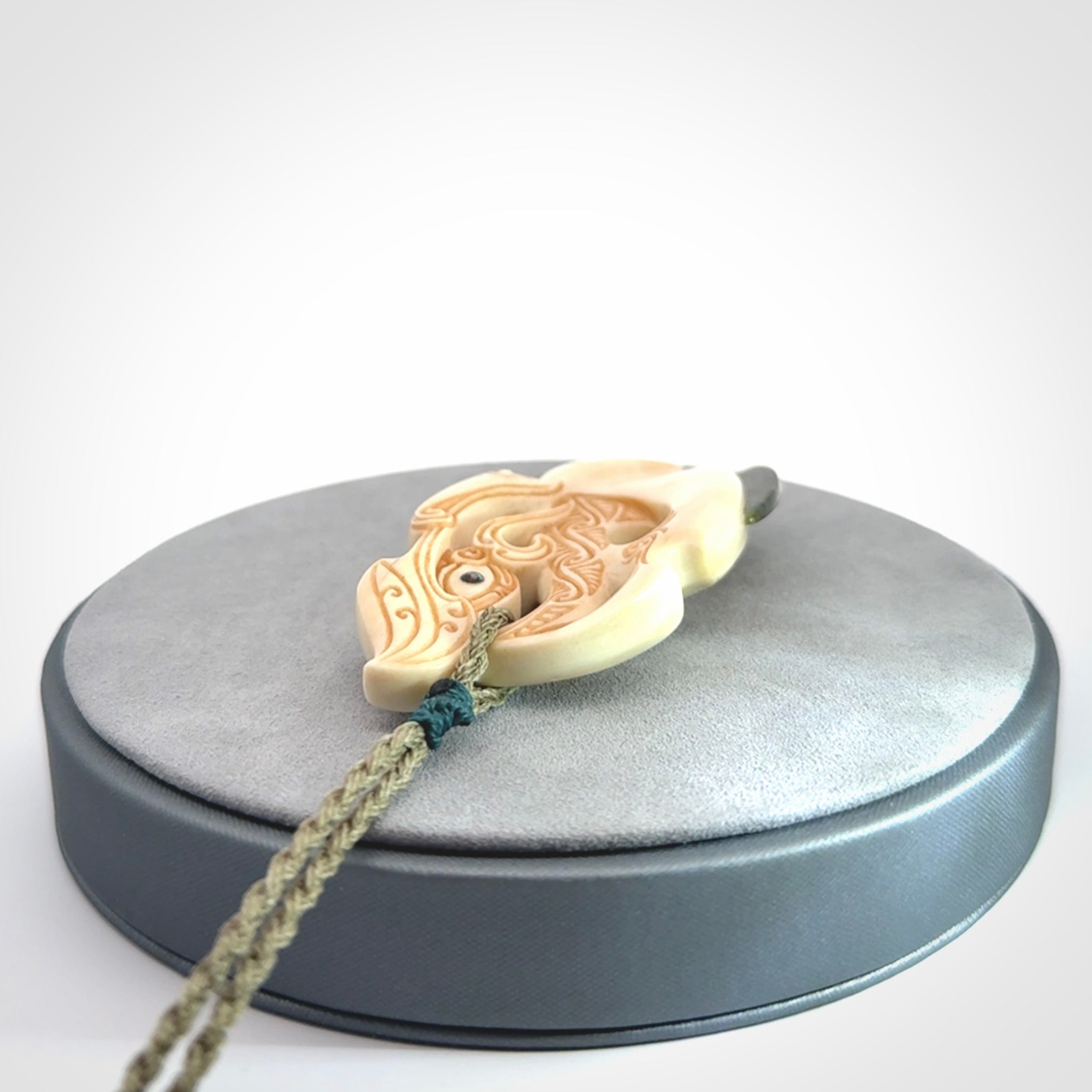 This picture shows a carved manaia in bone with Jade and Paua shell. It is provided with a hand-plaited fern green cord that is length adjustable. Free shipping worldwide.