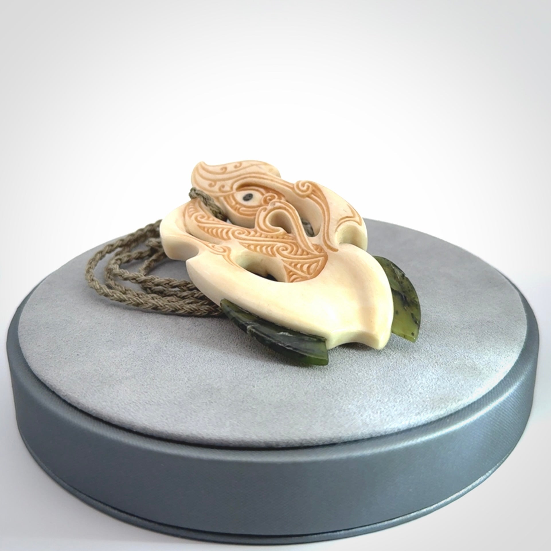 This picture shows a carved manaia in bone with Jade and Paua shell. It is provided with a hand-plaited fern green cord that is length adjustable. Free shipping worldwide.