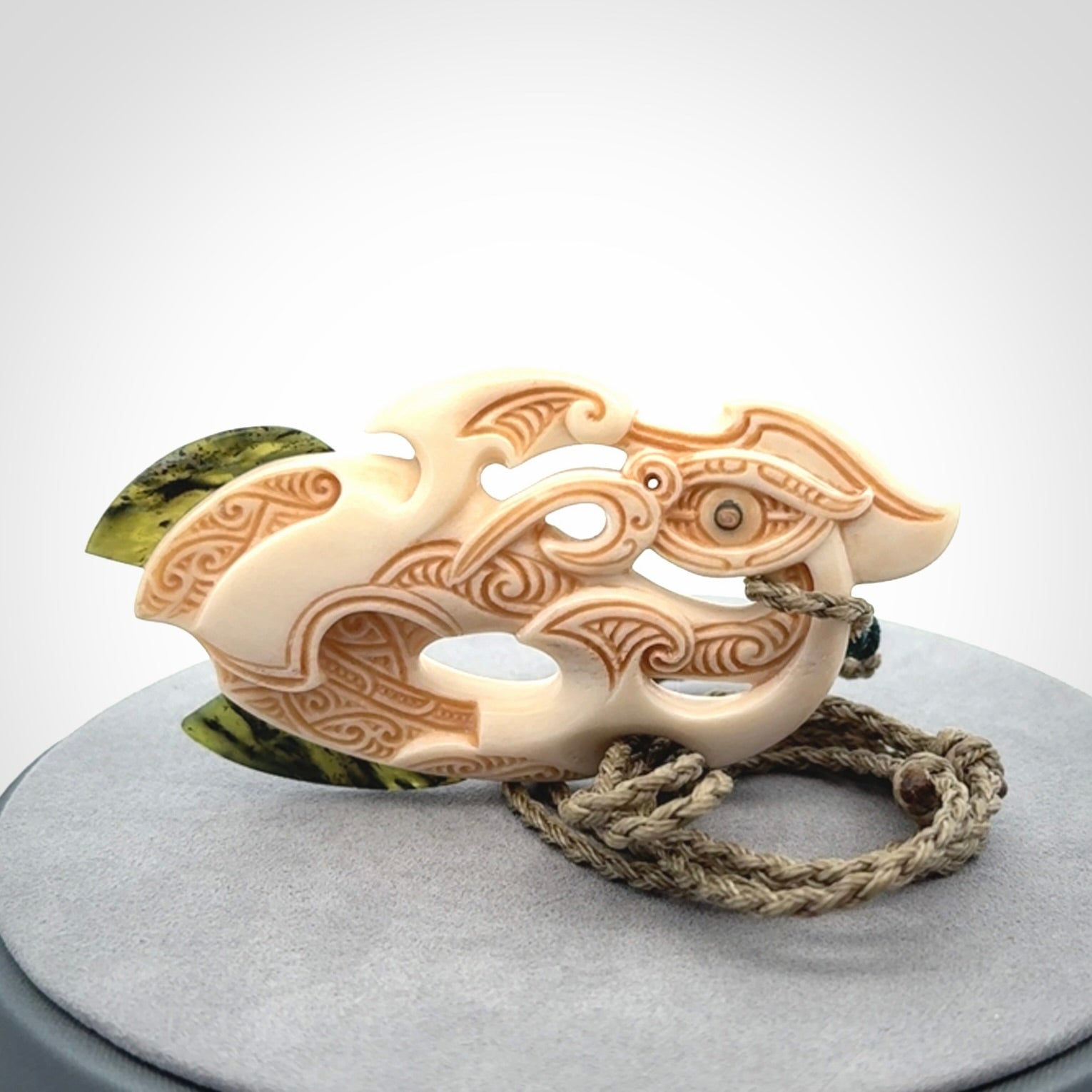 This picture shows a carved manaia in bone with Jade and Paua shell. It is provided with a hand-plaited fern green cord that is length adjustable. Free shipping worldwide.