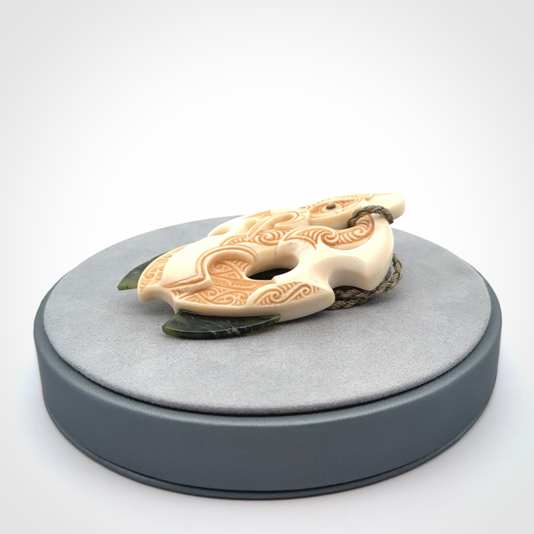 This picture shows a carved manaia in bone with Jade and Paua shell. It is provided with a hand-plaited fern green cord that is length adjustable. Free shipping worldwide.