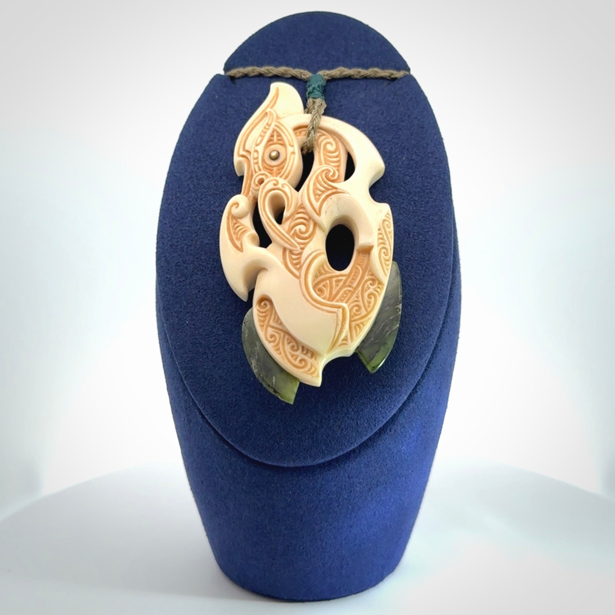 This picture shows a carved manaia in bone with Jade and Paua shell. It is provided with a hand-plaited fern green cord that is length adjustable. Free shipping worldwide.