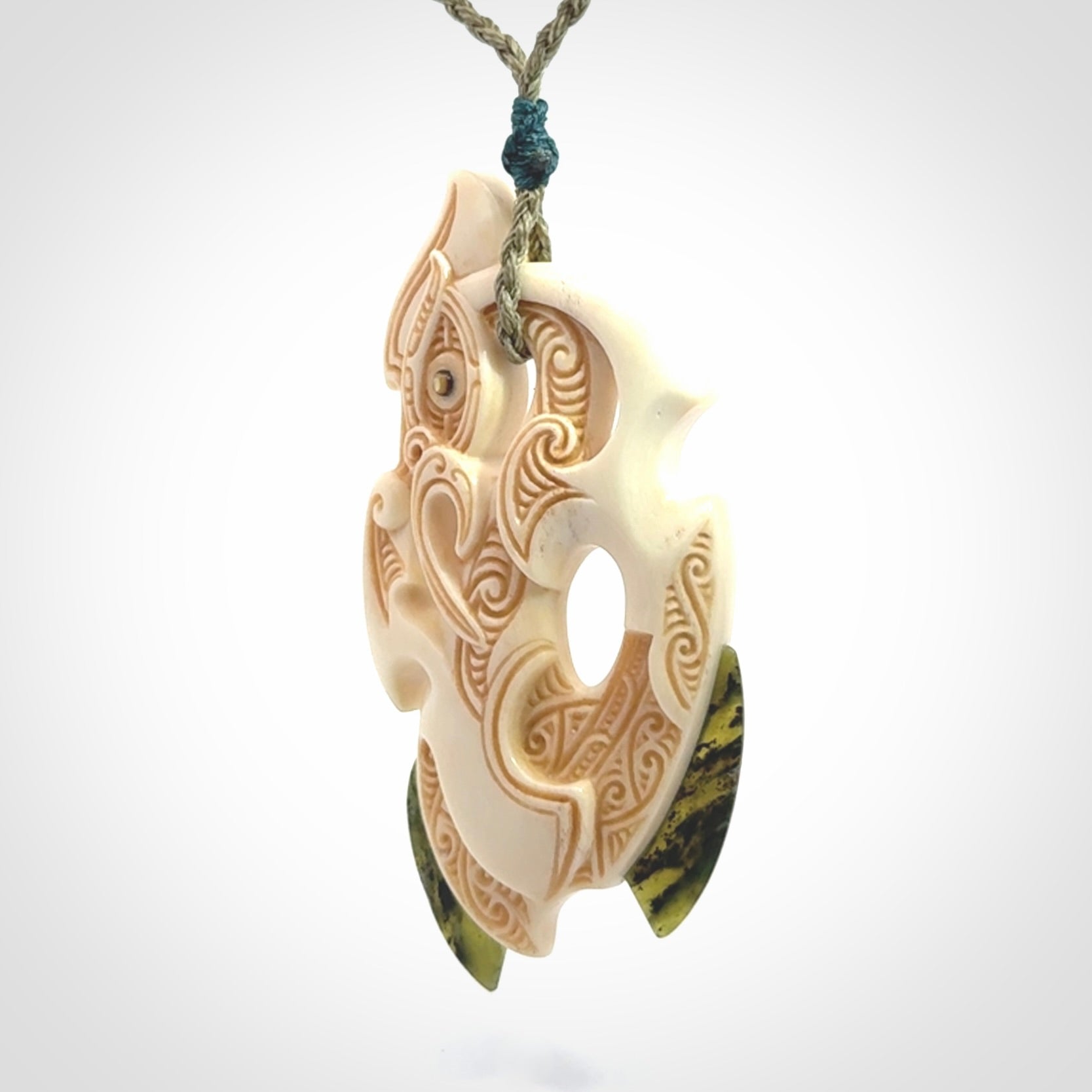 This picture shows a carved manaia in bone with Jade and Paua shell. It is provided with a hand-plaited fern green cord that is length adjustable. Free shipping worldwide.