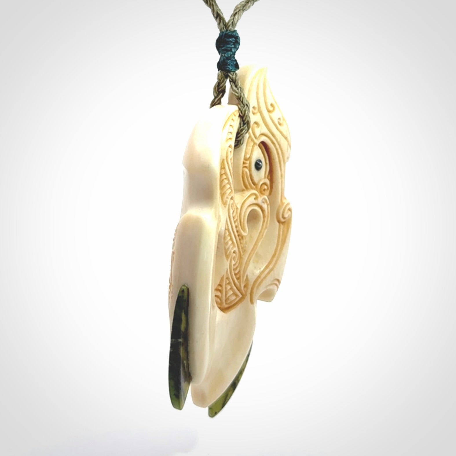 This picture shows a carved manaia in bone with Jade and Paua shell. It is provided with a hand-plaited fern green cord that is length adjustable. Free shipping worldwide.
