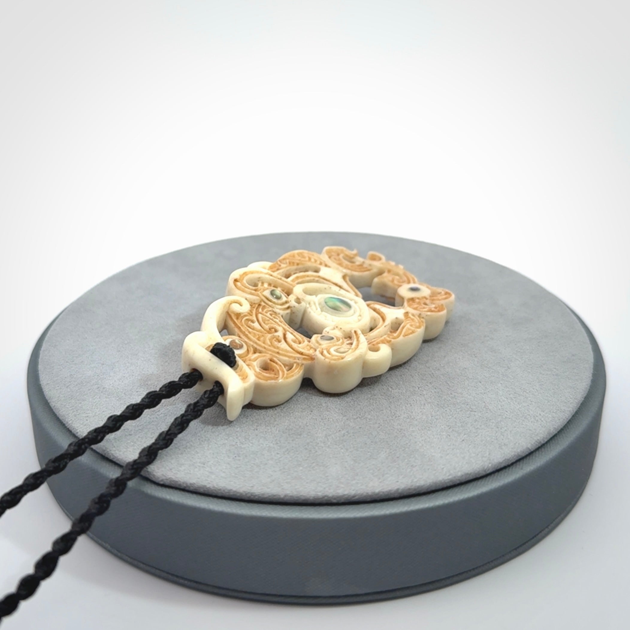 Hand carved bone manaia pendant with Jade, Mother of Pearl, Paua shell and Brass inlay. This is a complex carving by New Zealand carver and artist, Andrew Doughty. It is an intricate representation of a manaia carved to represent protection. It can be worn but is also a quality that warrants display.