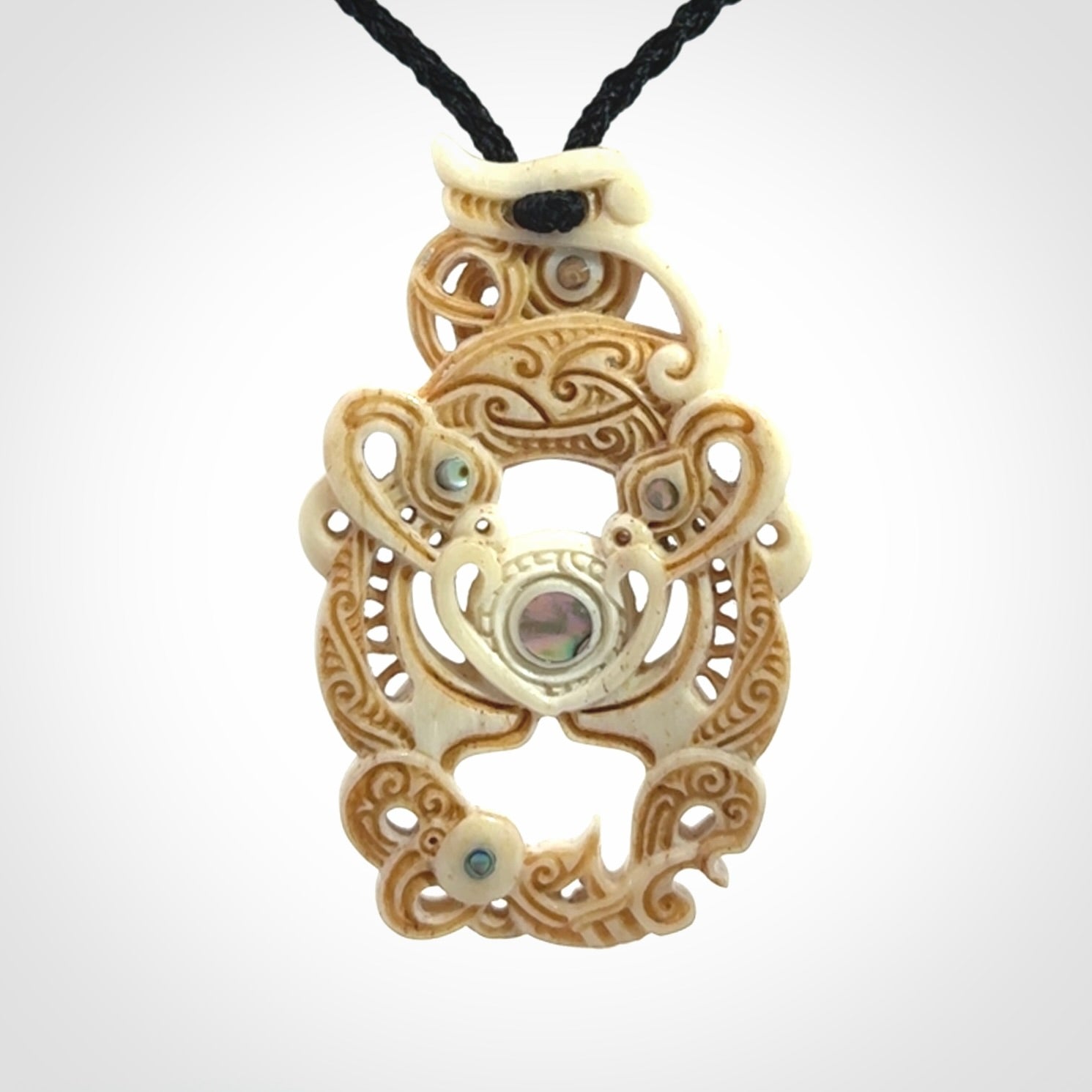 Hand carved bone manaia pendant with Jade, Mother of Pearl, Paua shell and Brass inlay. This is a complex carving by New Zealand carver and artist, Andrew Doughty. It is an intricate representation of a manaia carved to represent protection. It can be worn but is also a quality that warrants display.