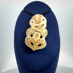 This picture shows a carved Tiki pendant in bone. It is provided with a hand-plaited black cord that is length adjustable.