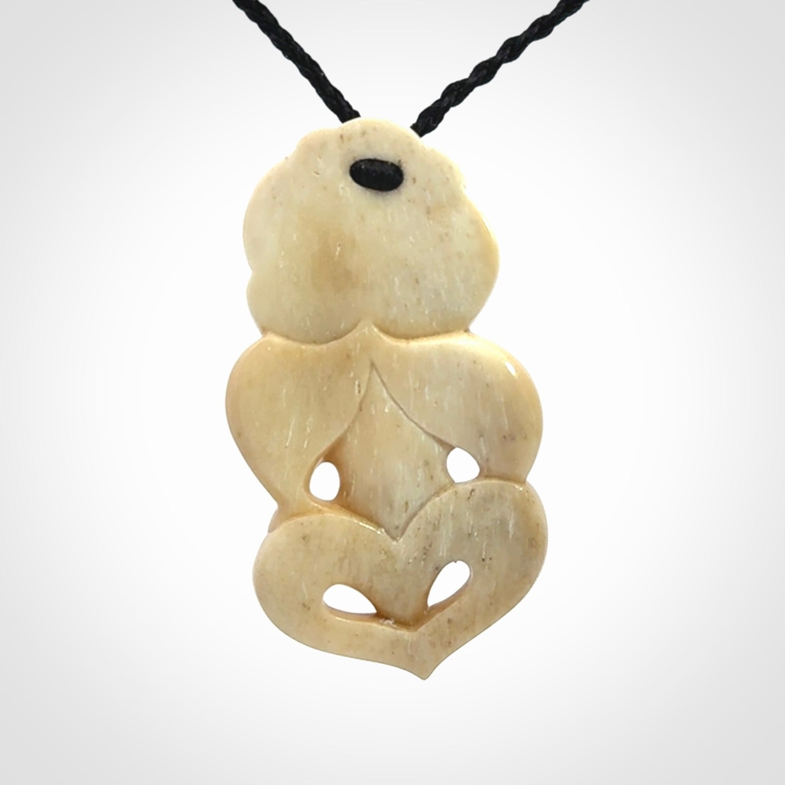 This picture shows a carved Tiki pendant in bone. It is provided with a hand-plaited black cord that is length adjustable.
