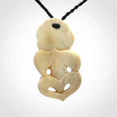 This picture shows a carved Tiki pendant in bone. It is provided with a hand-plaited black cord that is length adjustable.